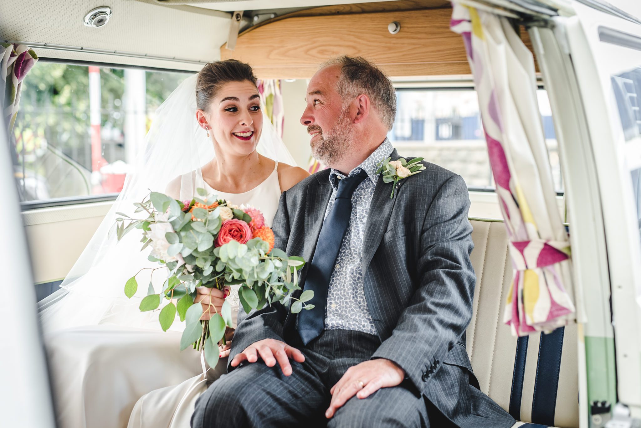 bride and her father sat in a vw camper van