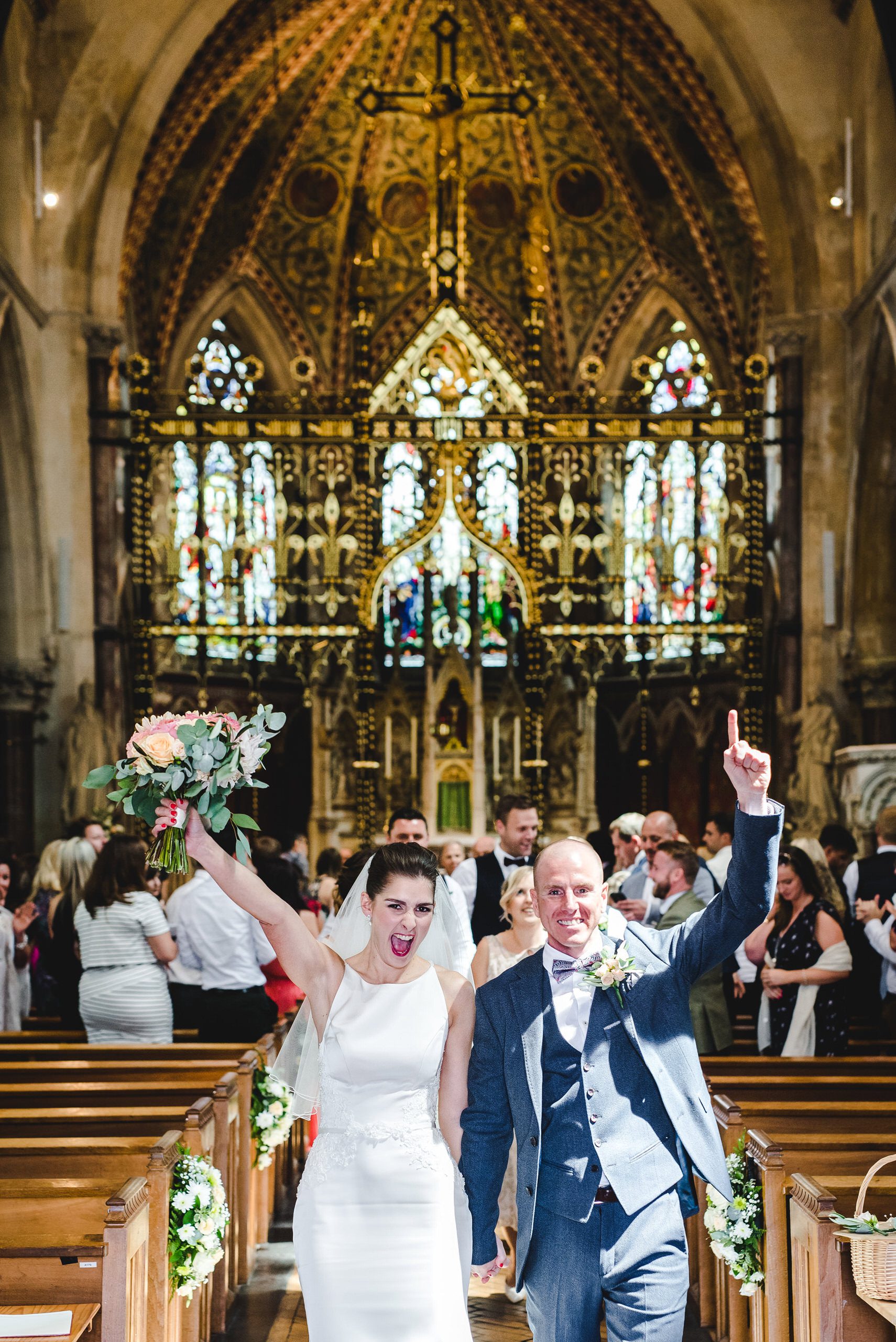 bride and groom with their arms in the air leaving a church