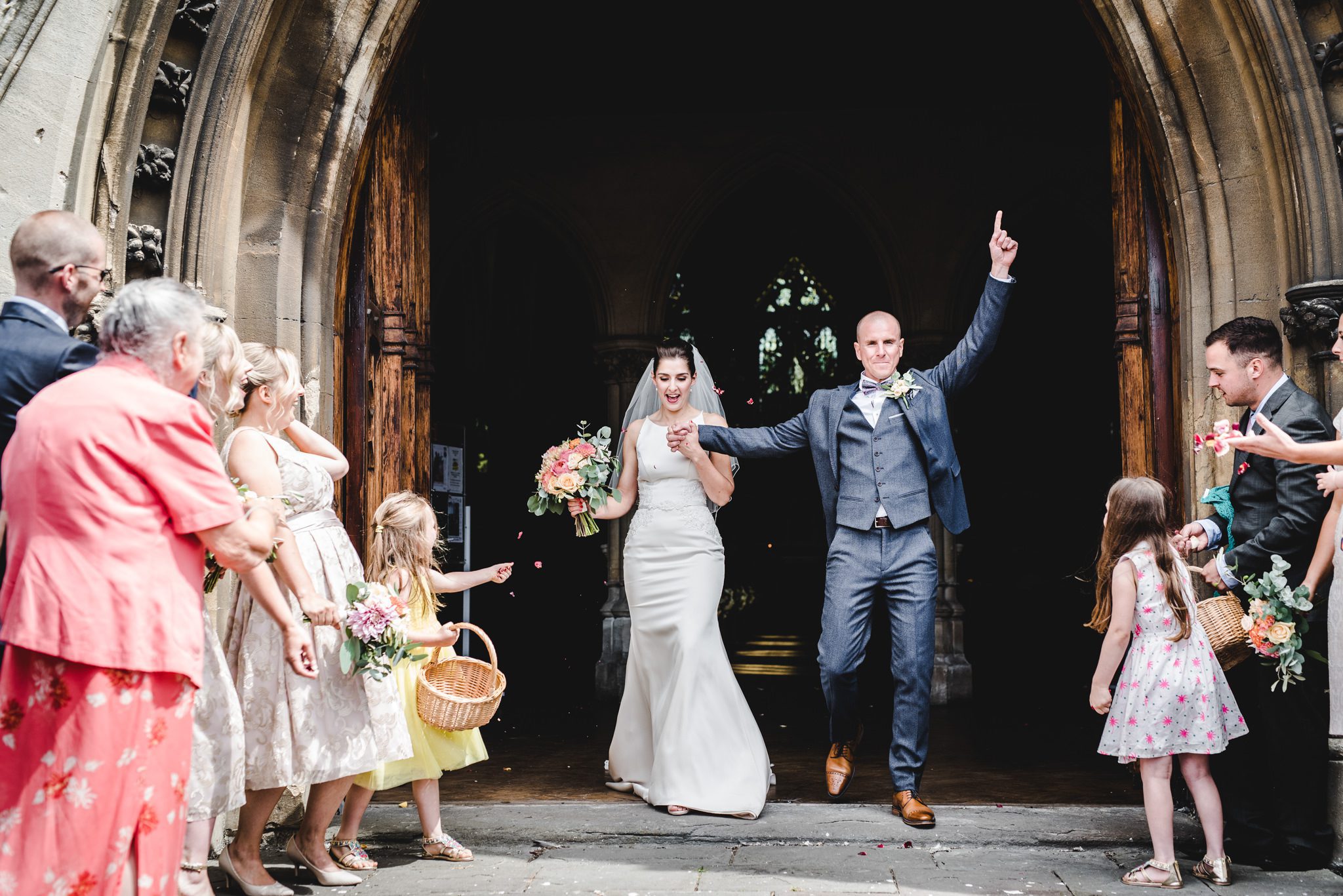 groom raising his hands aloft leaving a wedding ceremony