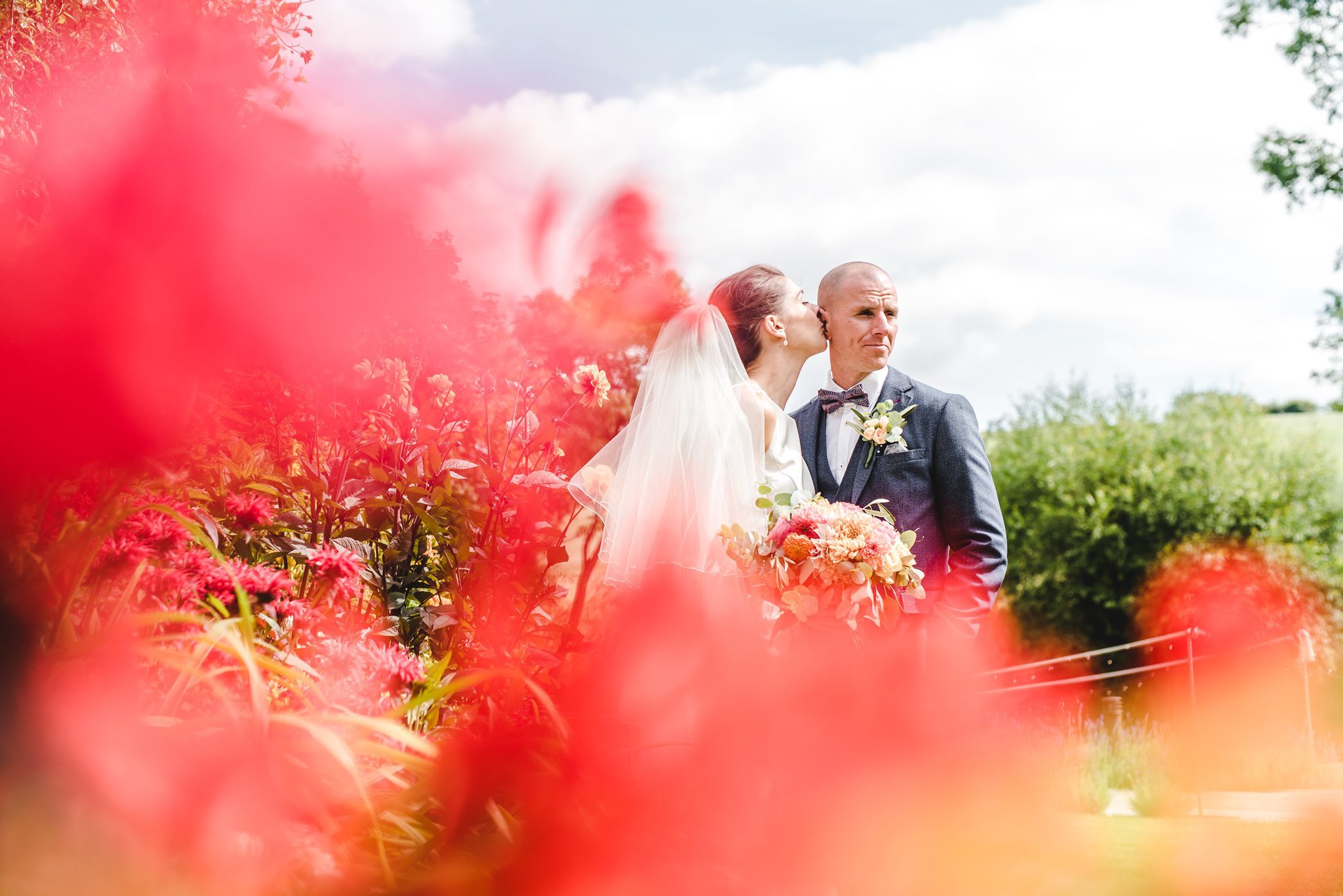 a bride and groom surrounded by flowers at priston mill