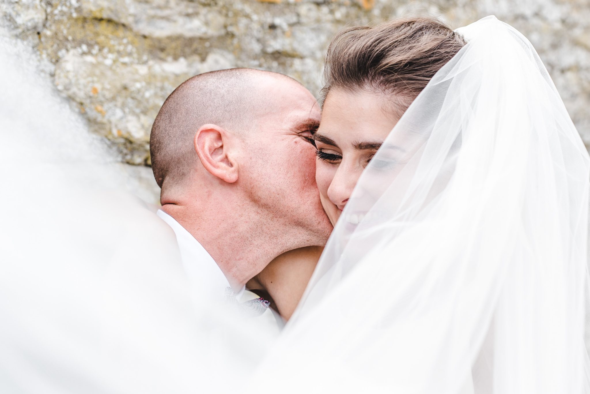 a groom kissing a bride at priston mill