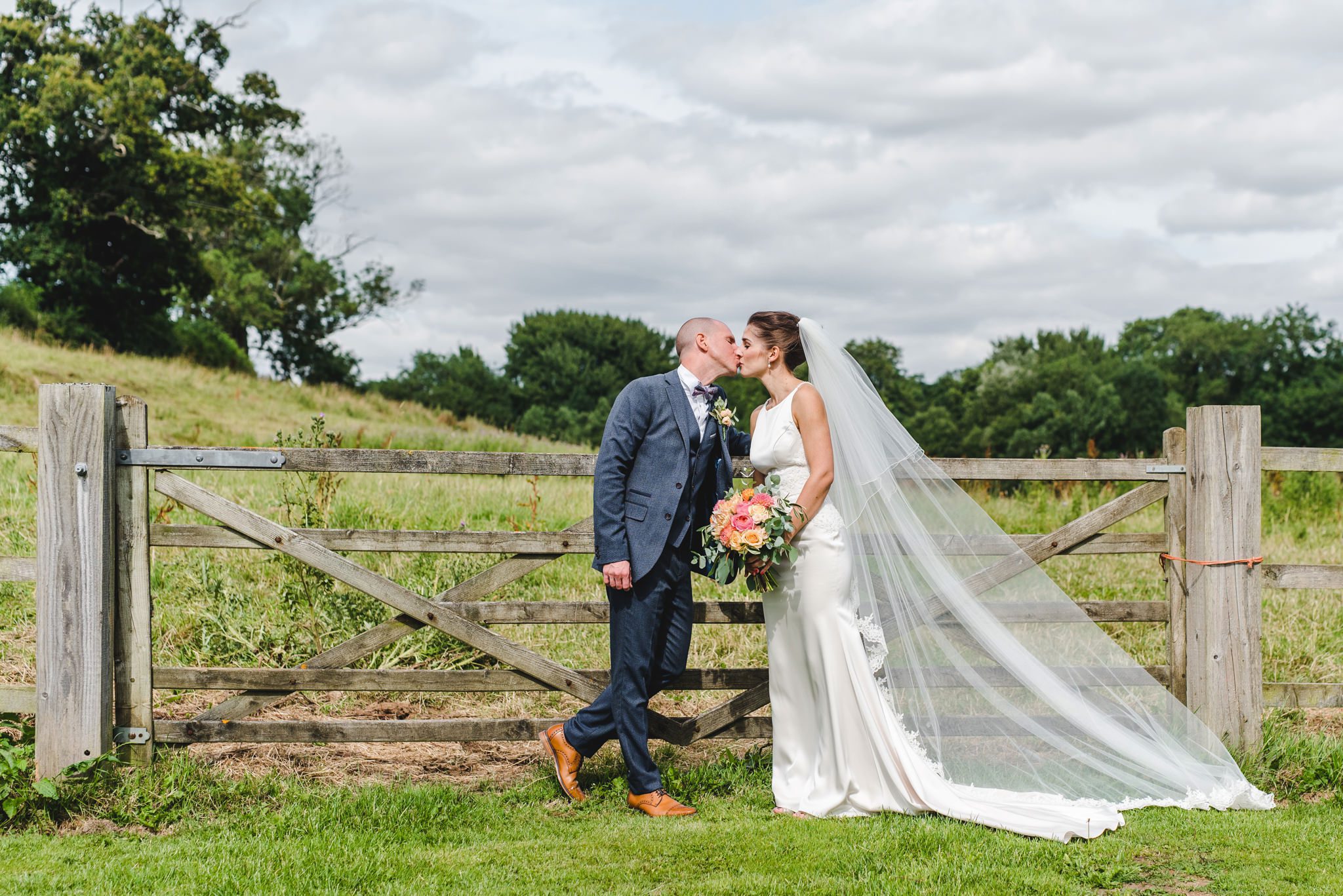 bride and groom at priston mill wedding standing by a gate