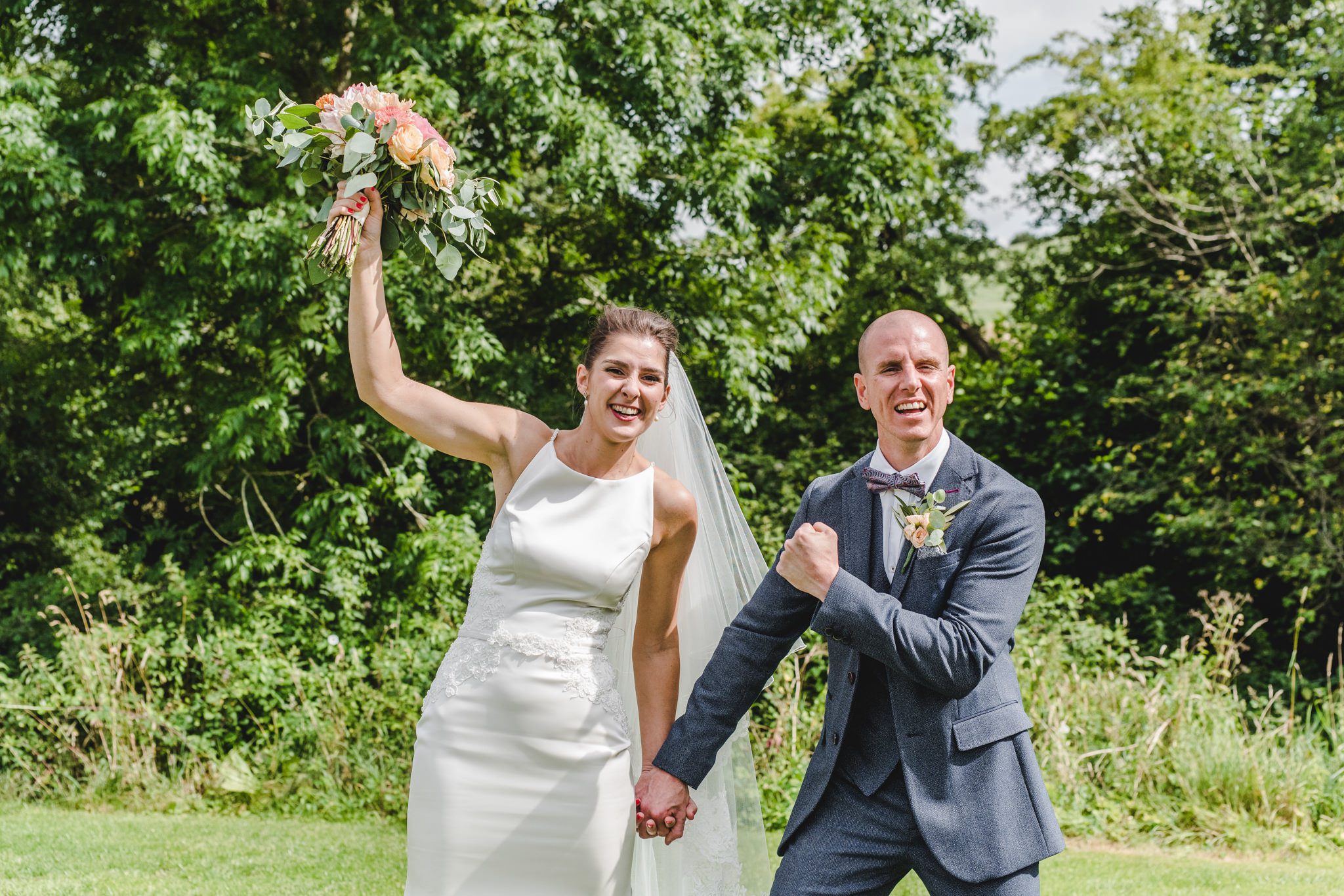 a bride and groom punching the air in celebration