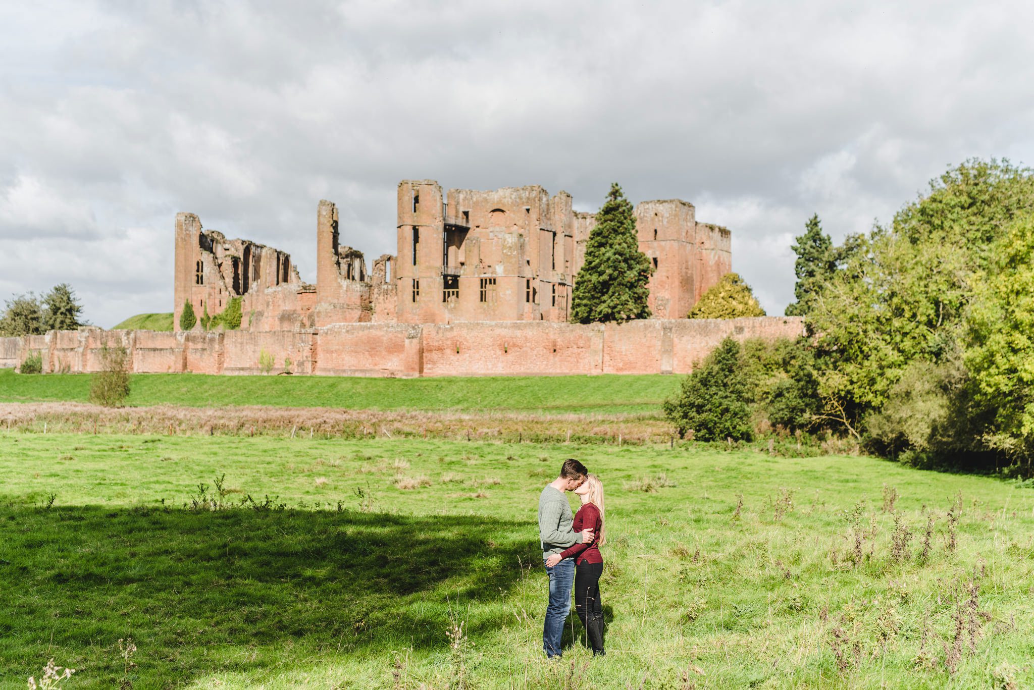 a couple standing in the shadow of Kenilworth Castle