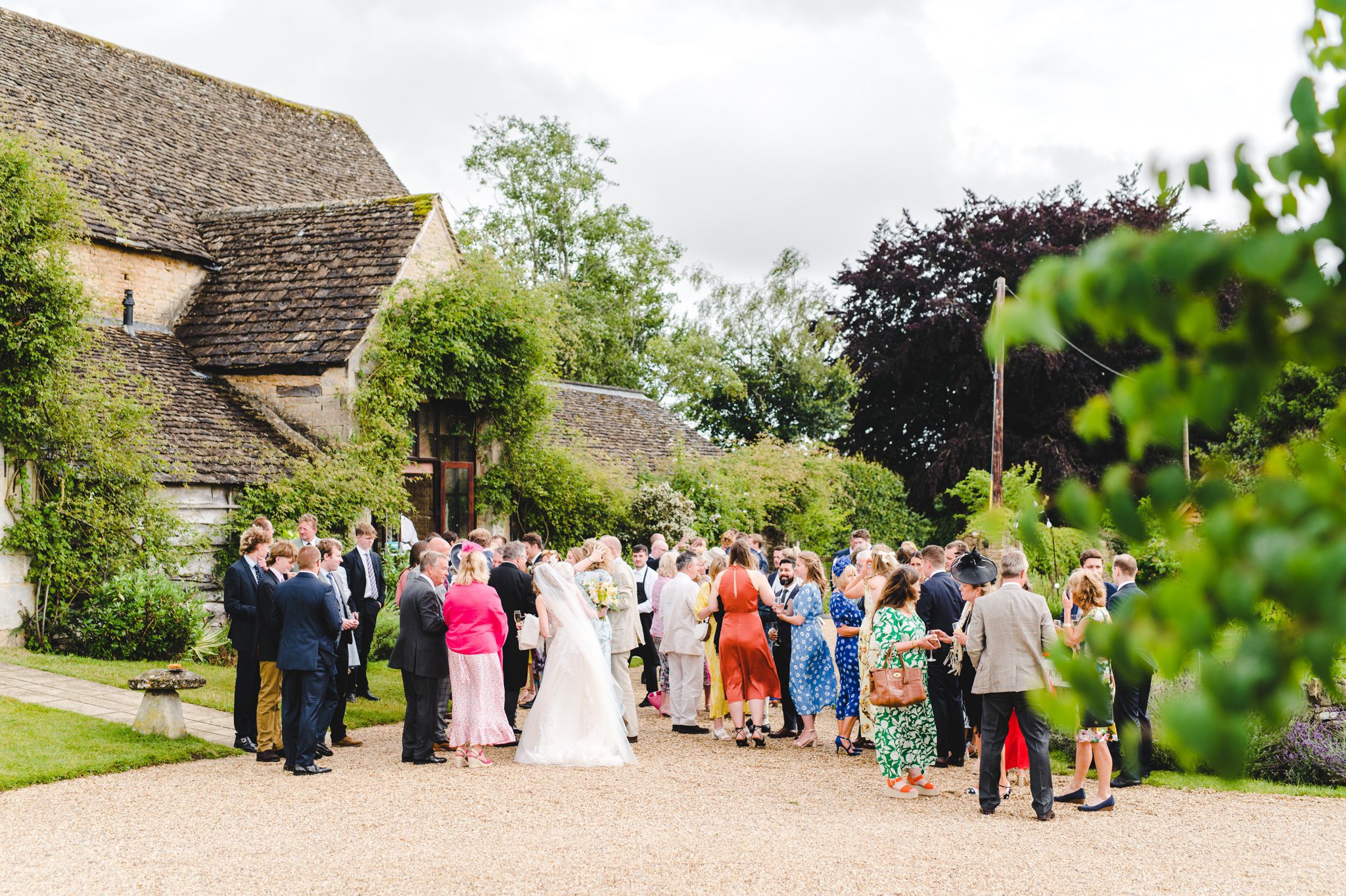 Wedding guests gathering for their drinks reception at their barn wedding in Gloucestershire