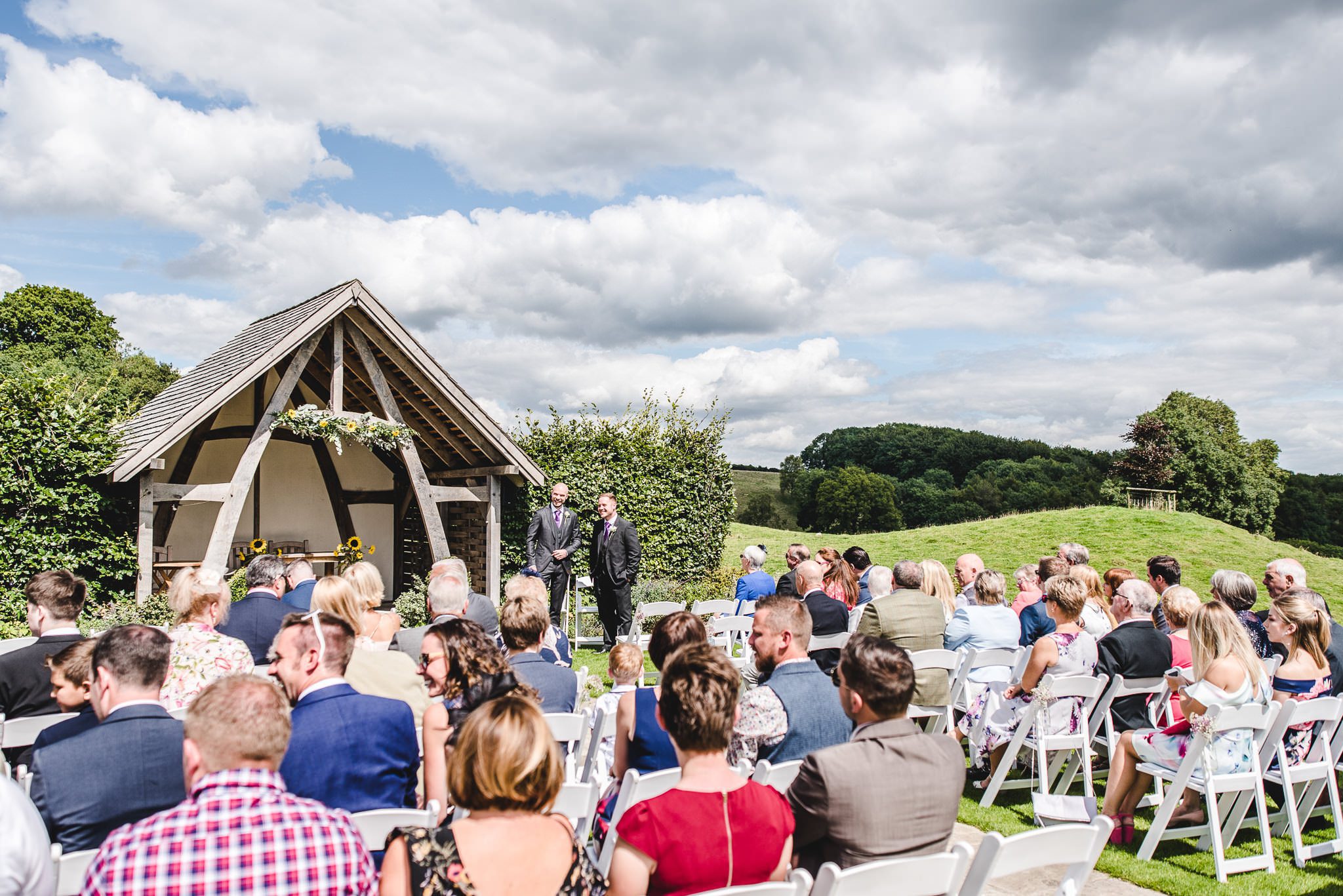 A groom standing at the altar at Kingscote Barn outdoor wedding venue waiting for his bride