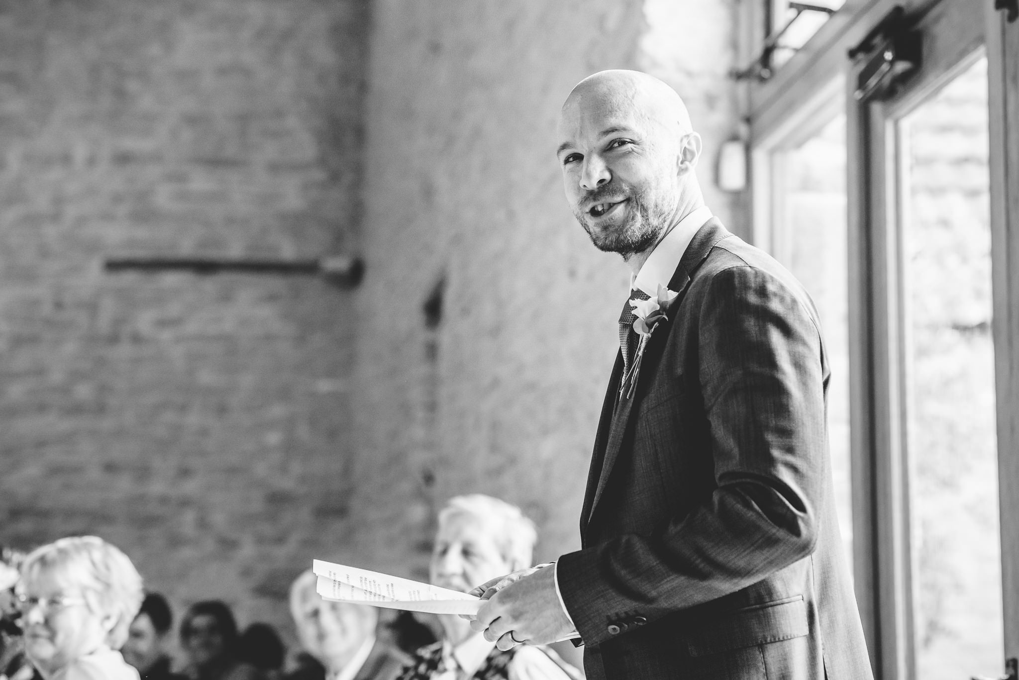 A black and white image of a groom doing his speech