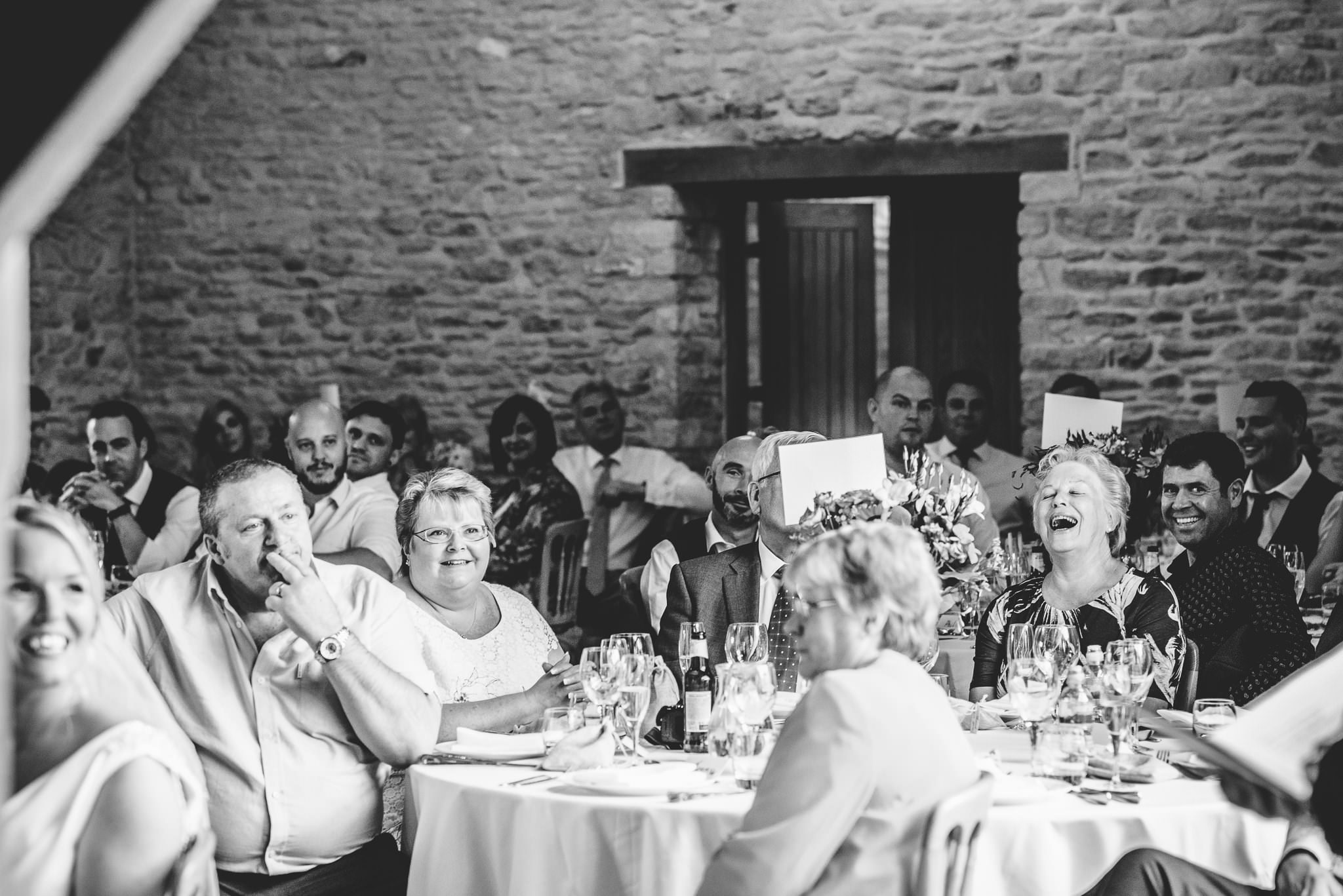 Wedding guests lauging at speeches at Kingscote Barn