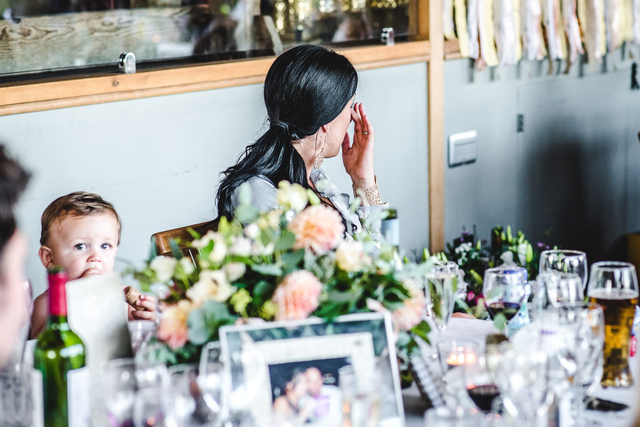 Sister of the groom wipingaway tears at a wedding