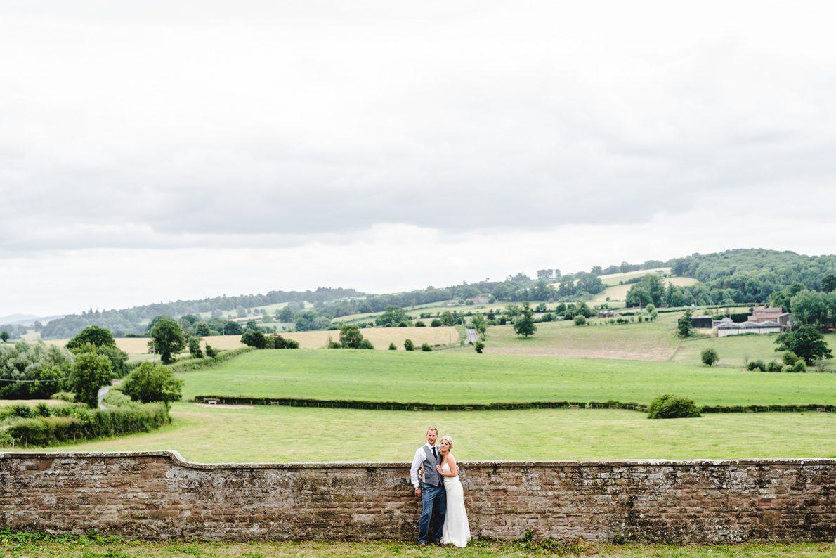 A newly married couple in Gloucestershire standing by a wall