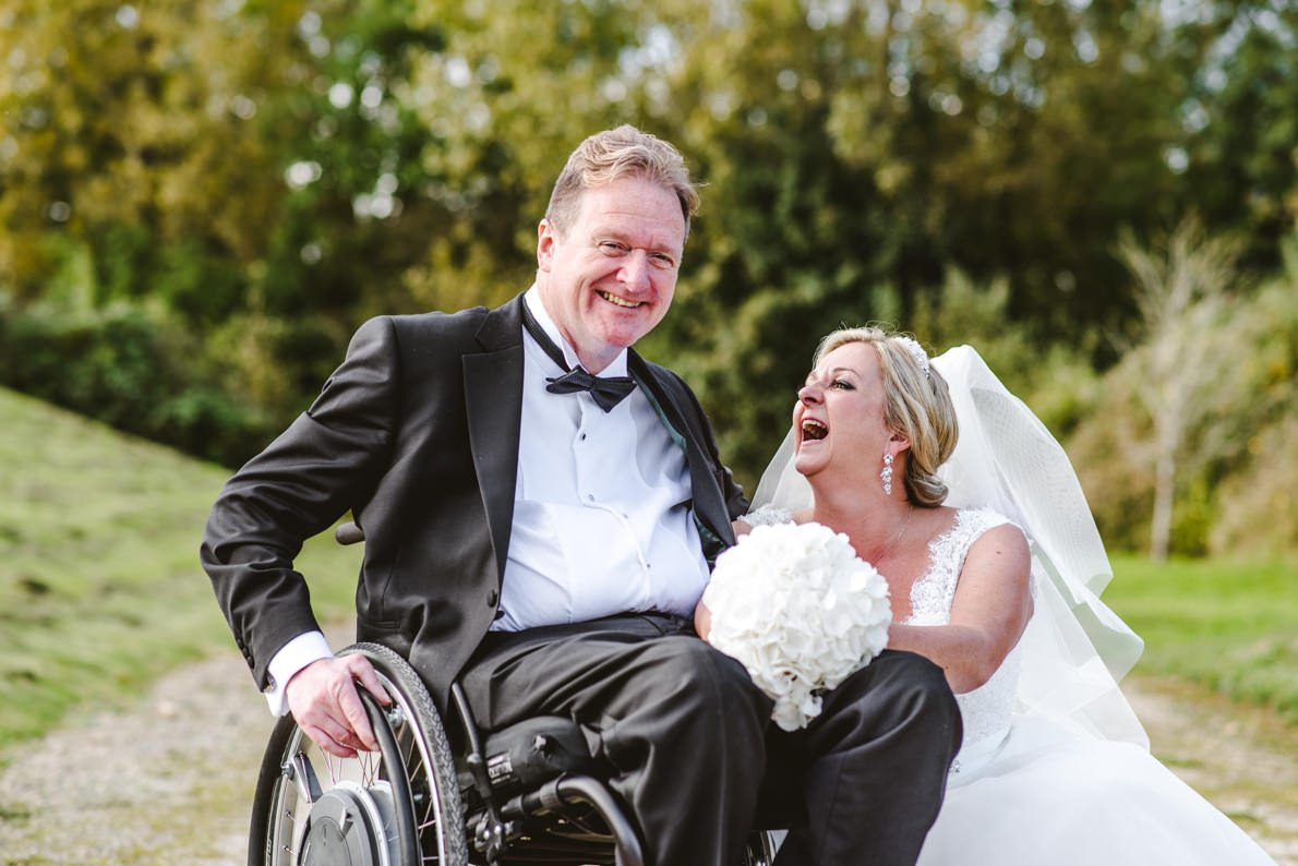 A disabled wedding couple laughing next to the wheelchair