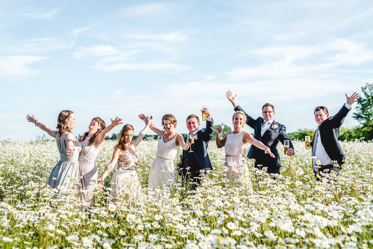 A group photo at a wedding in a field of daisies - Great Tythe Barn Photography