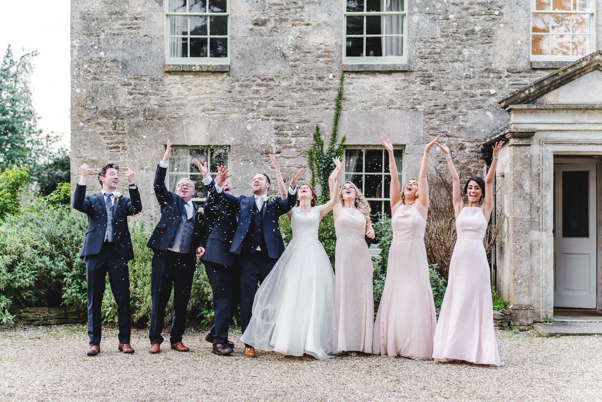 Wedding party throwing confetti outside great tythe house