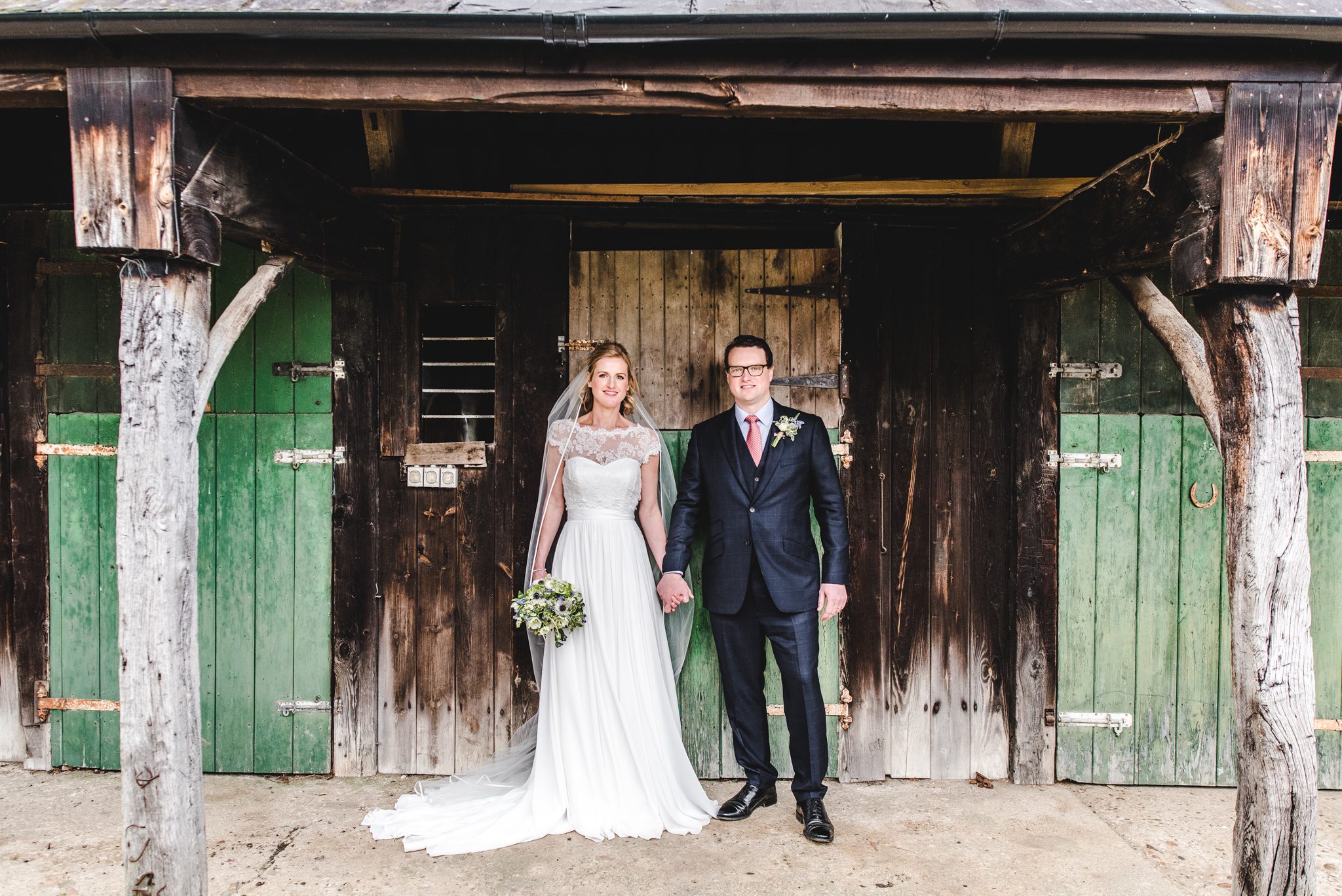 Bride and Groom standing against the stable doors