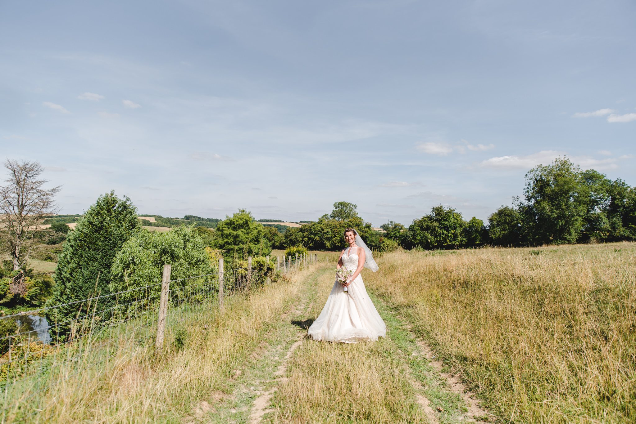 Bride standing in a field at Upcote Barn