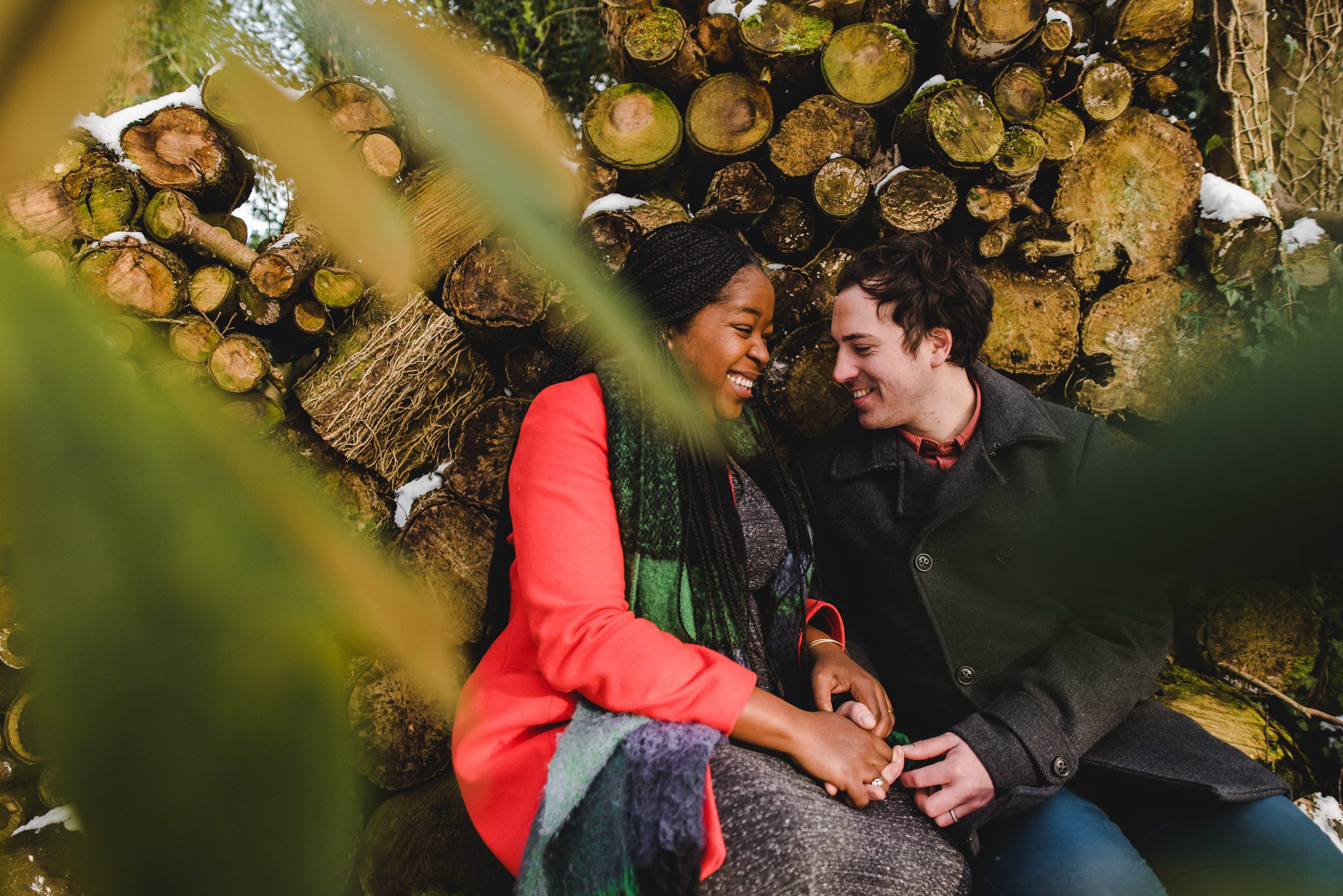 A couple sitting by a log pile in the snow at Matara