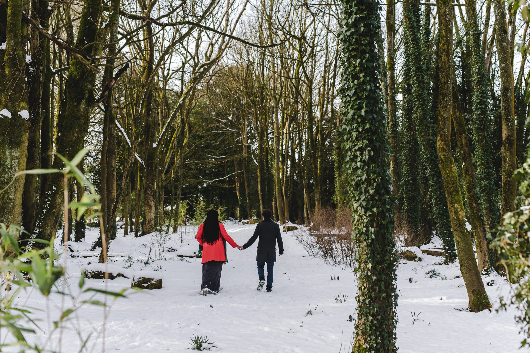 A couple walking hand in hand in a snowy forest
