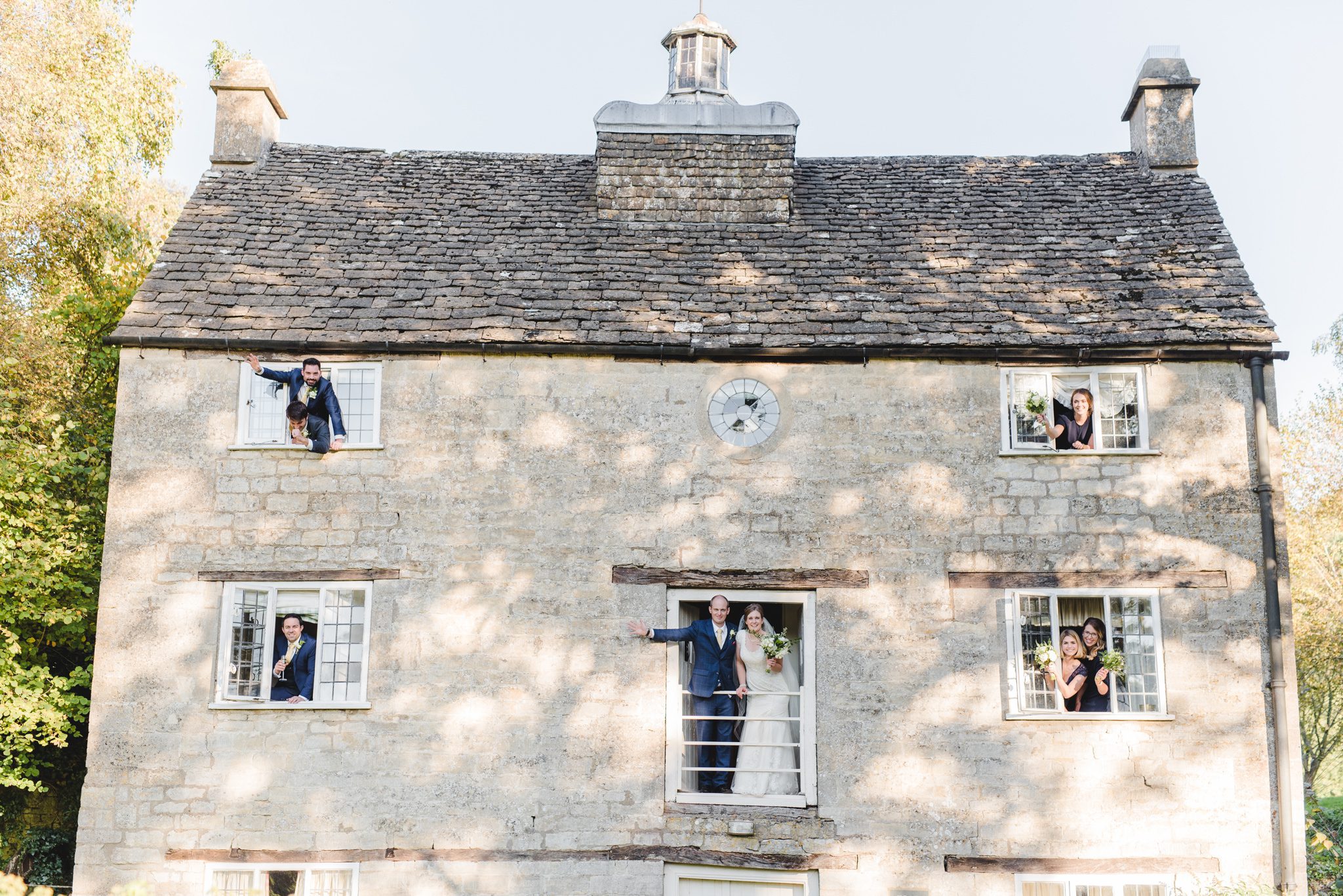 Wedding guests hanging out the windows of Grist Mill at Owlpen