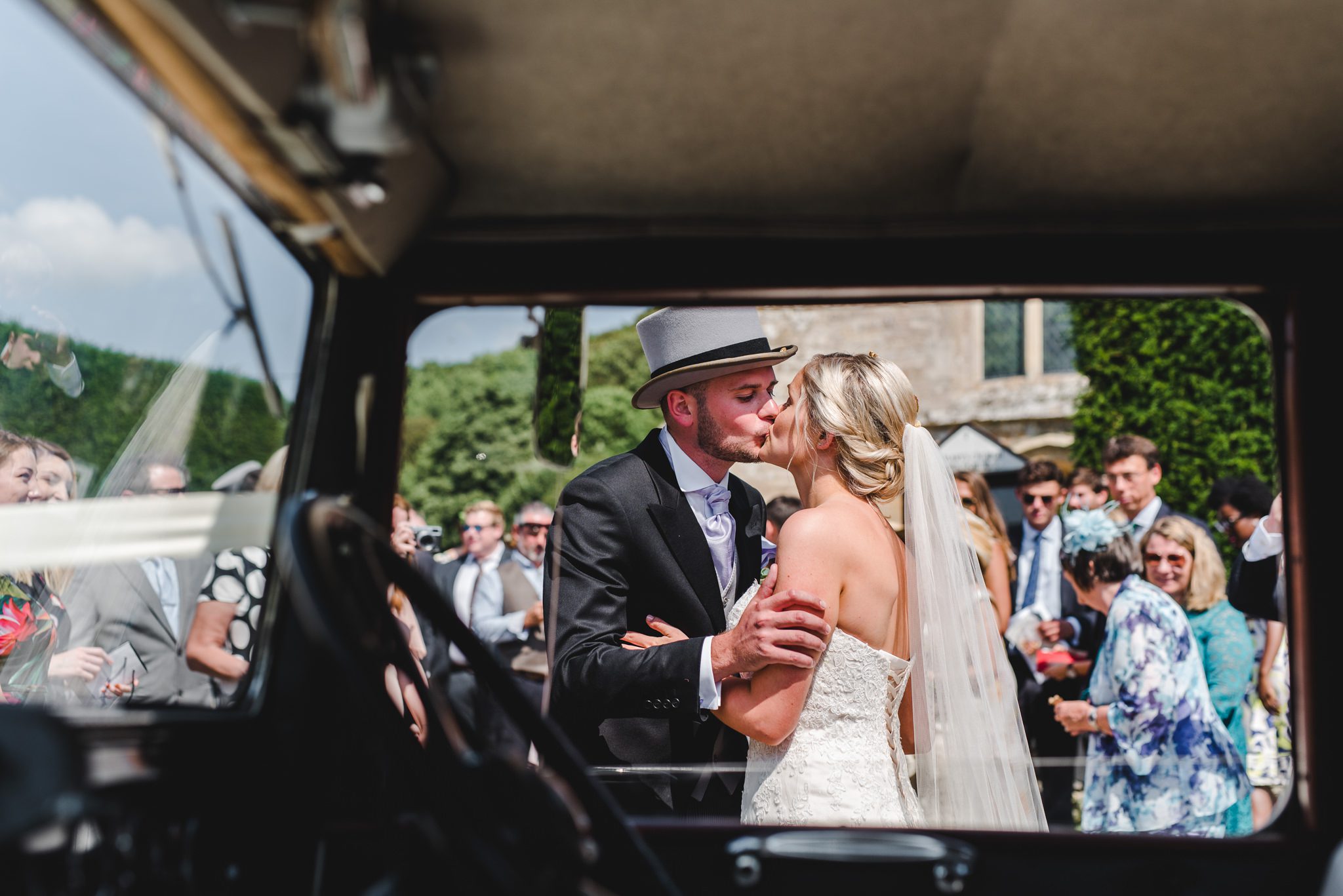 A bride and groom kissing through an open window in Gloucestershire