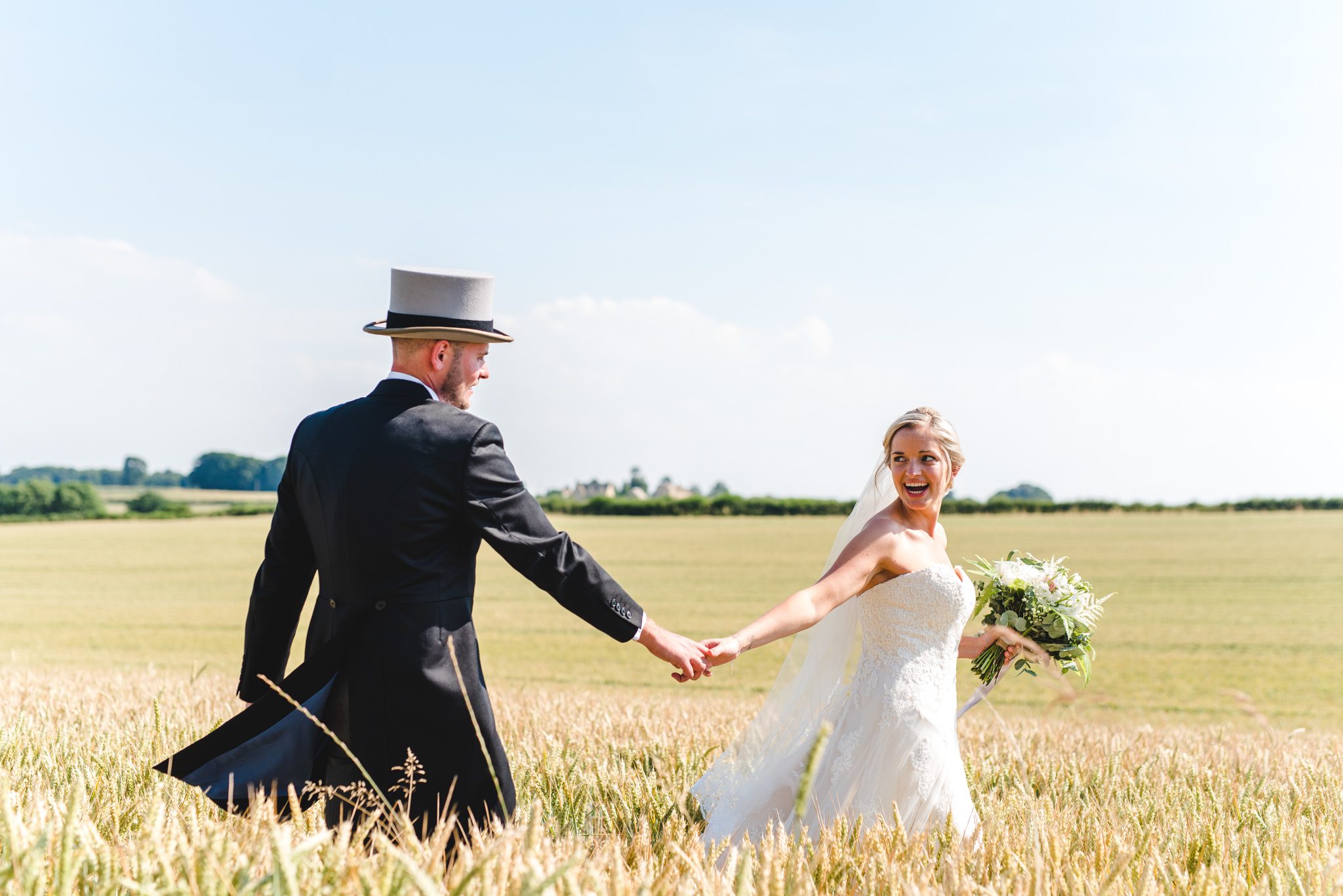 A bride leading her groom through a cornfield