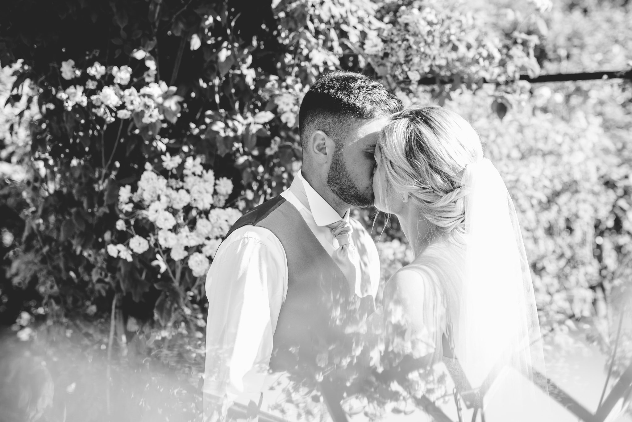 A kiss under the arbor between a bride and groom