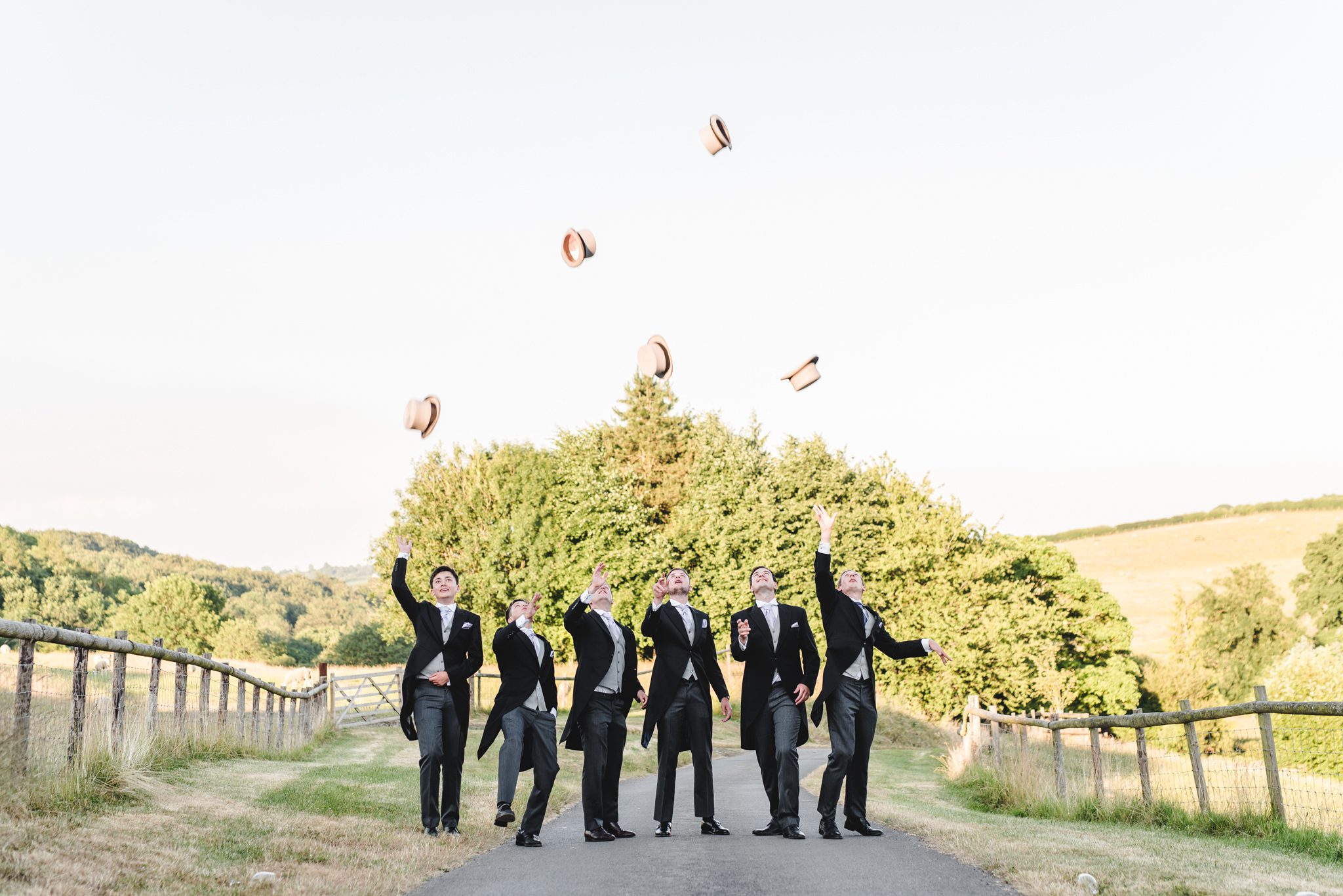 Groomsmen throwing their hats in the air at kingscote barn