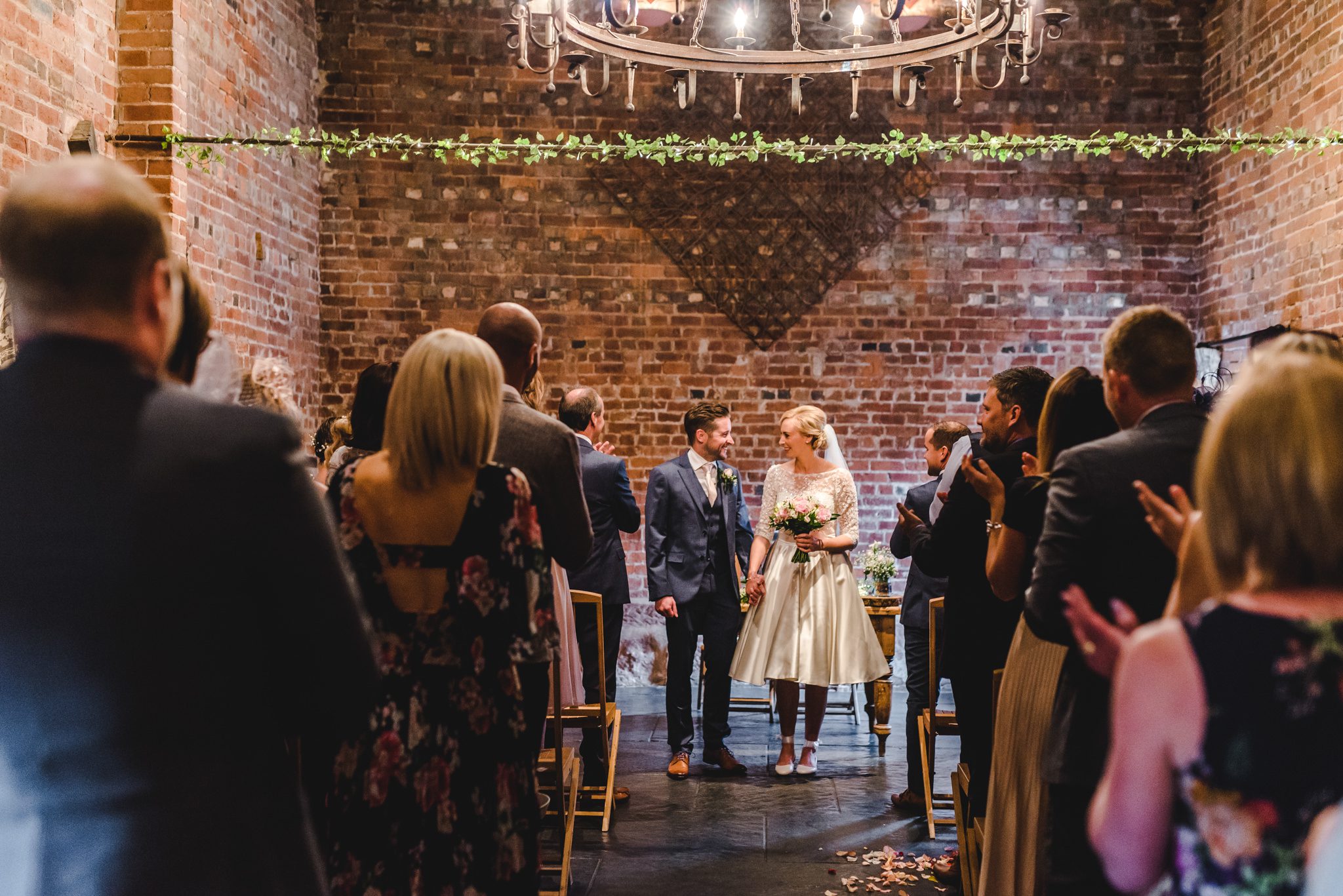 Bride and groom walking back down the aisle smiling at curradine barns