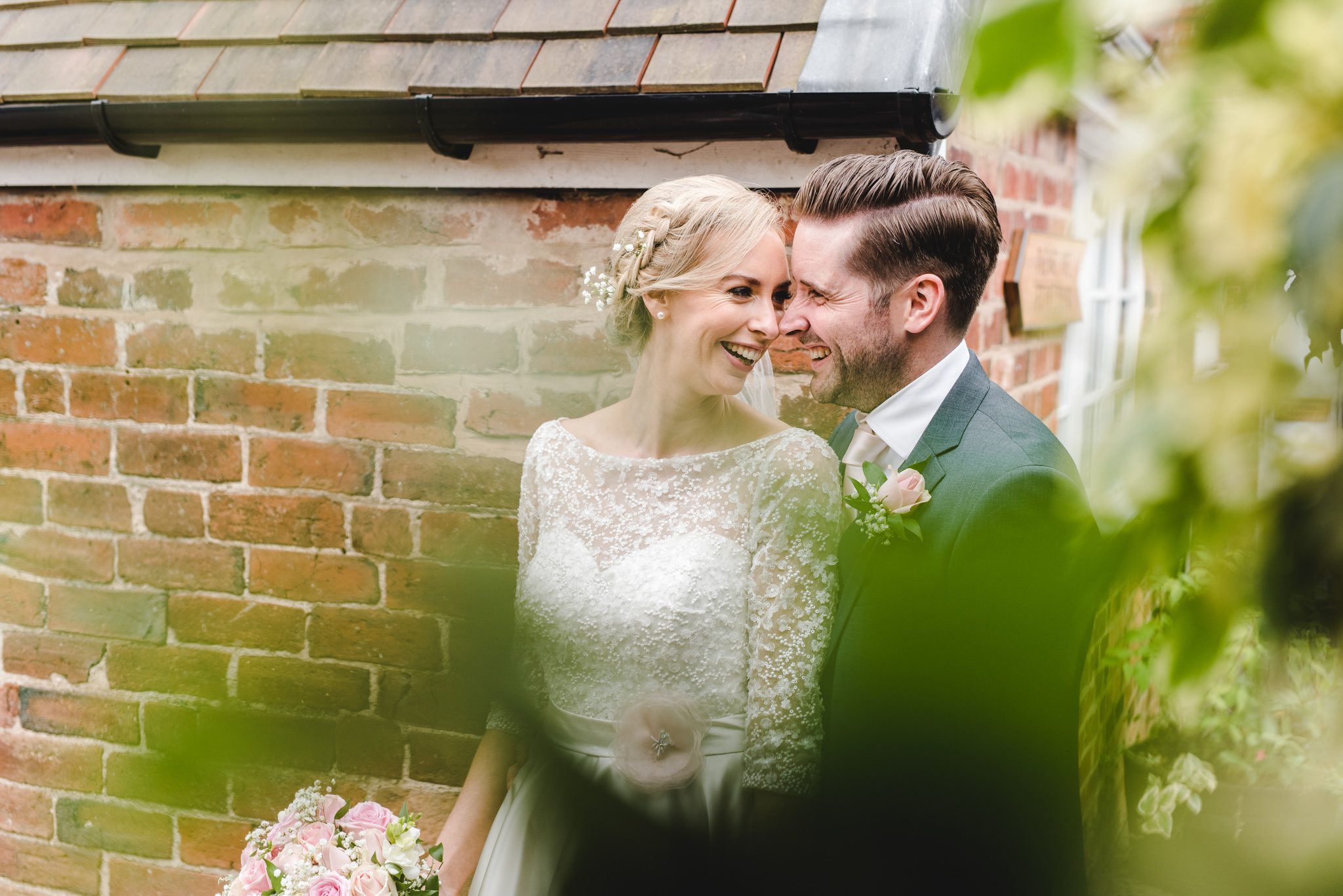 A couple smiling at each other during their wedding photographs at Curradine Barns