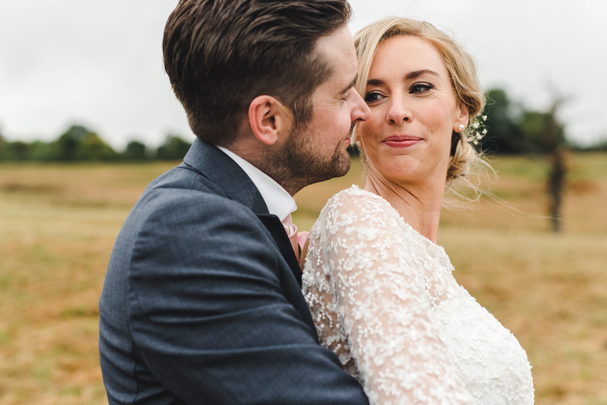 A groom standing behind his bride at their Curradine Barns wedding