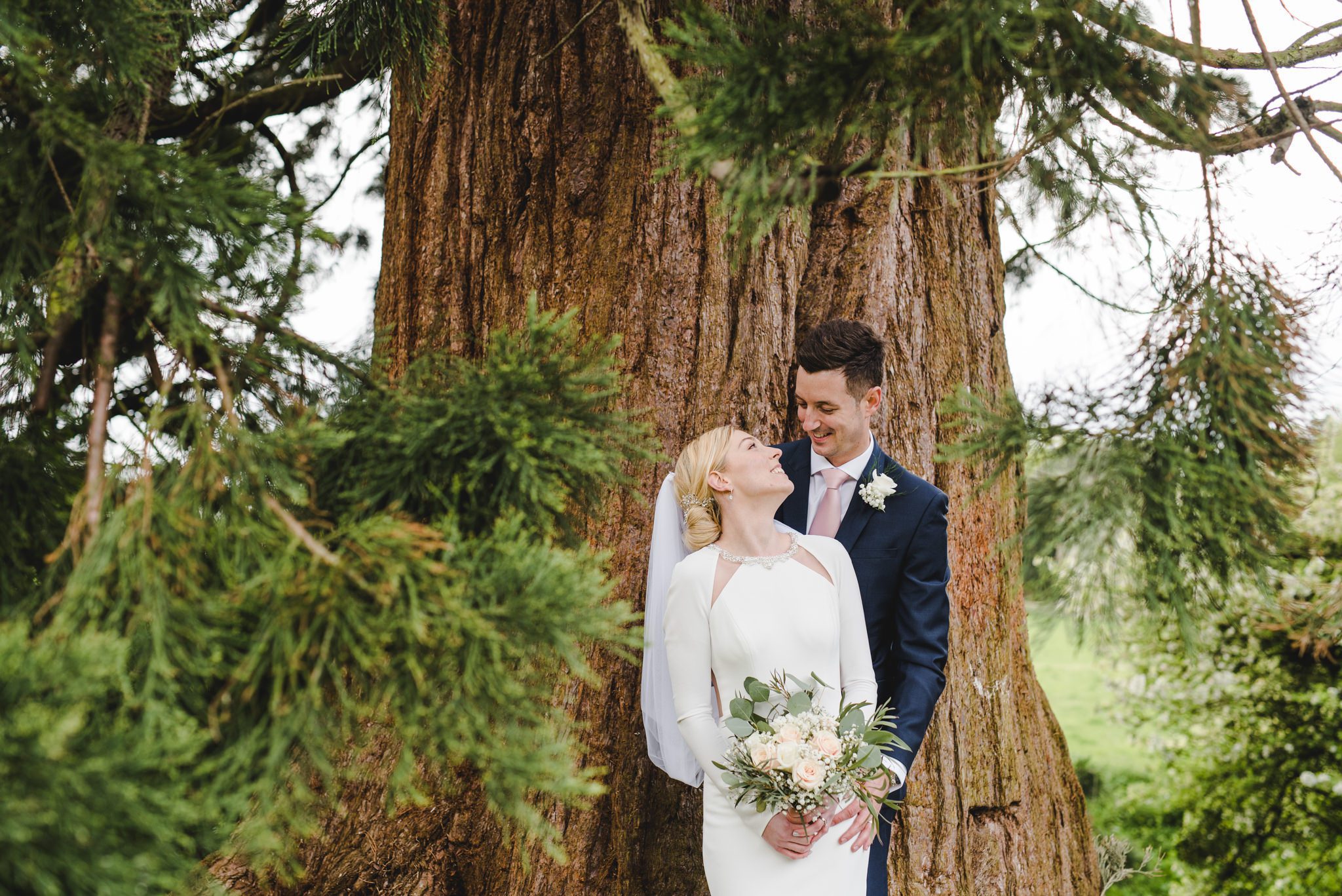 A bride and groom close together in gardens