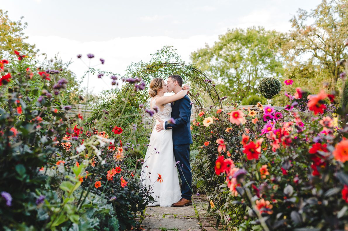 a married couple in teh gardens at oxleaze surrounded by colourful flowers
