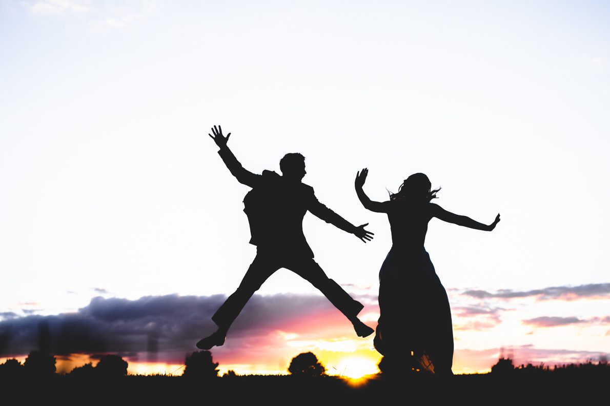 a silhouette of a bride and groom at sunset