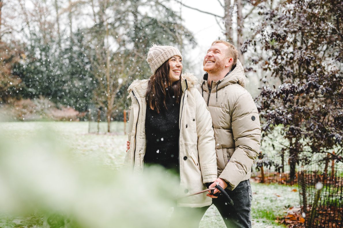 A winter engagement shoot with a couple walking their dog in the snow at Westonbirt Arboretum