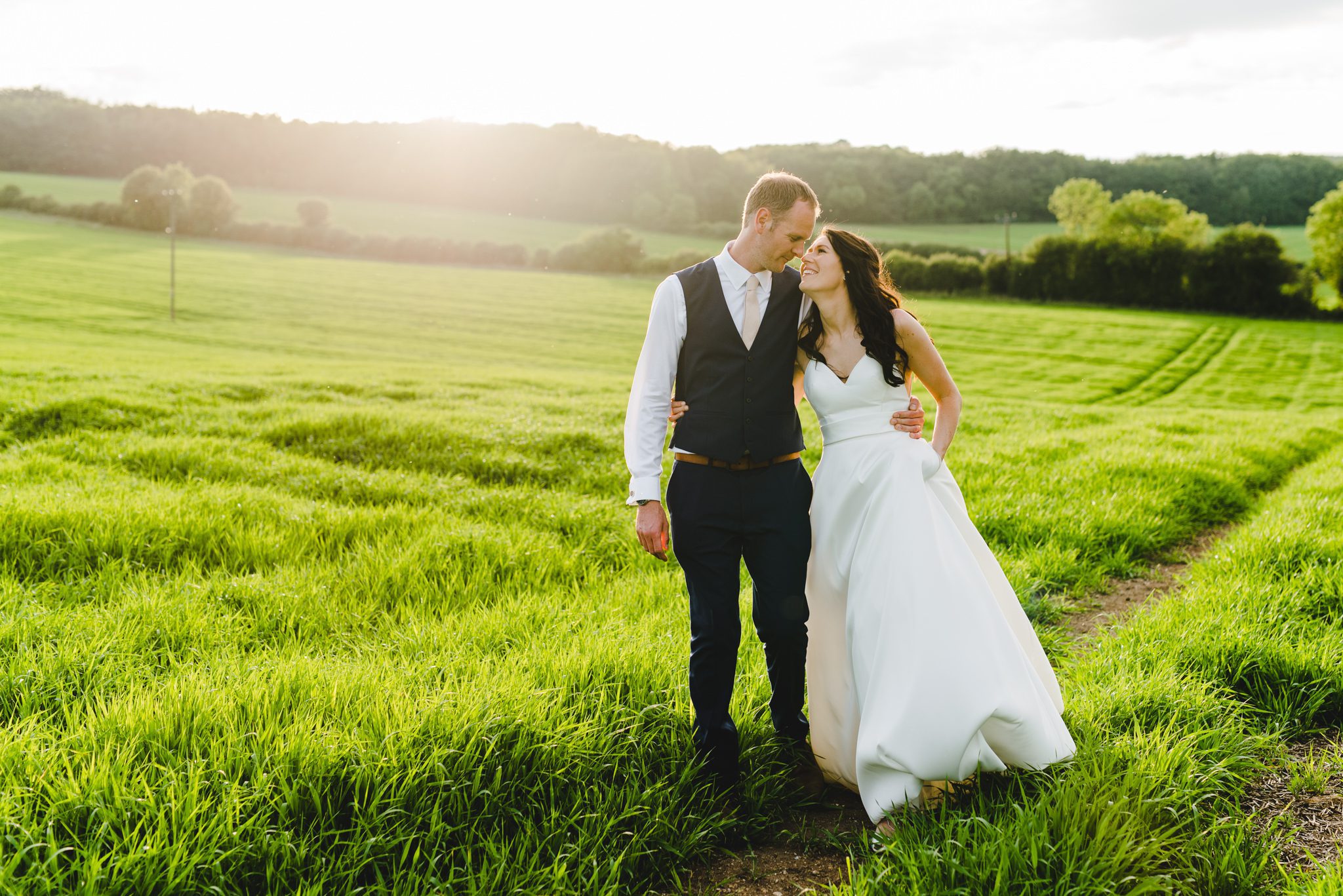 A couple at their upcote barn wedding in a field