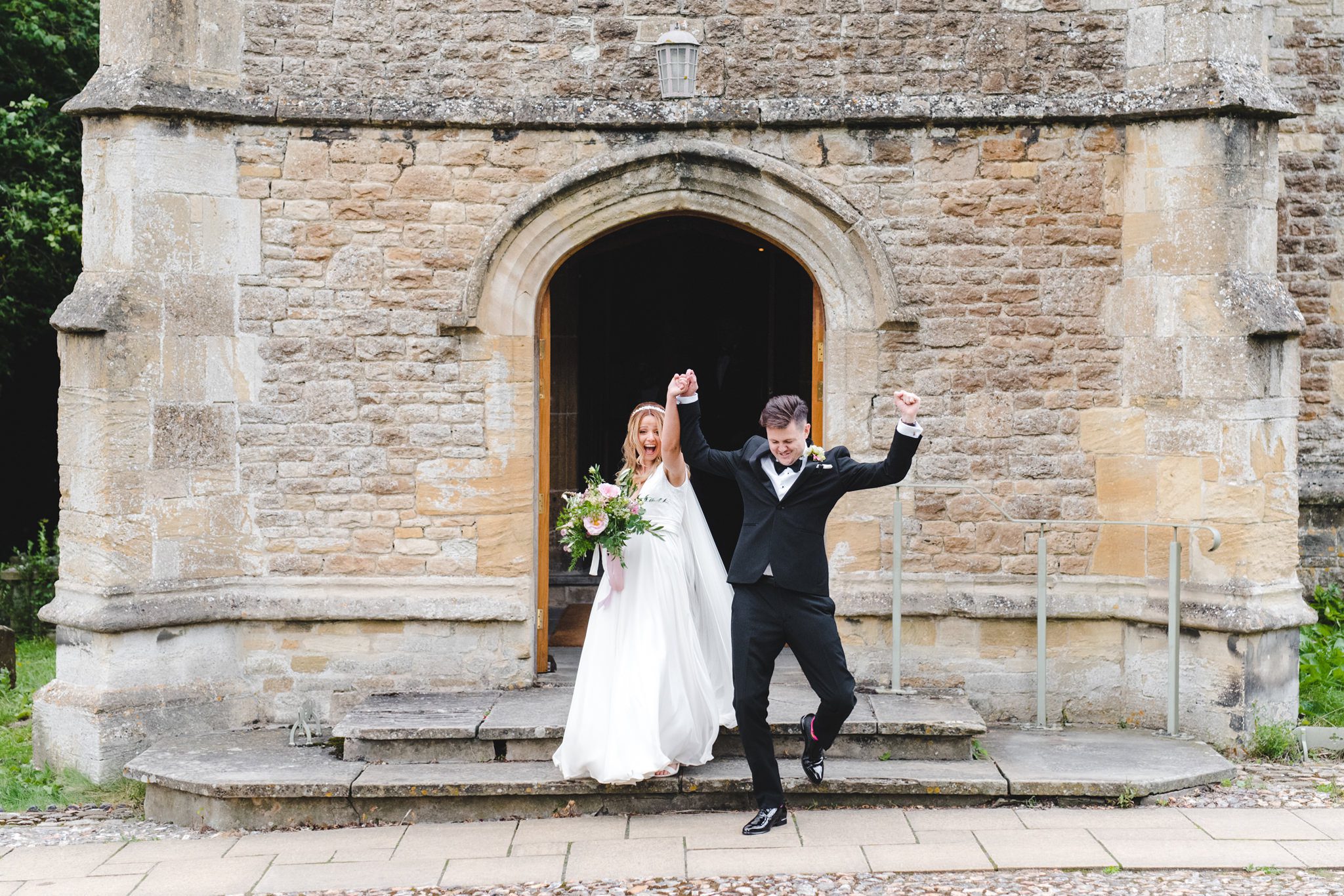 Bride and groom exiting the church with their arms in the air
