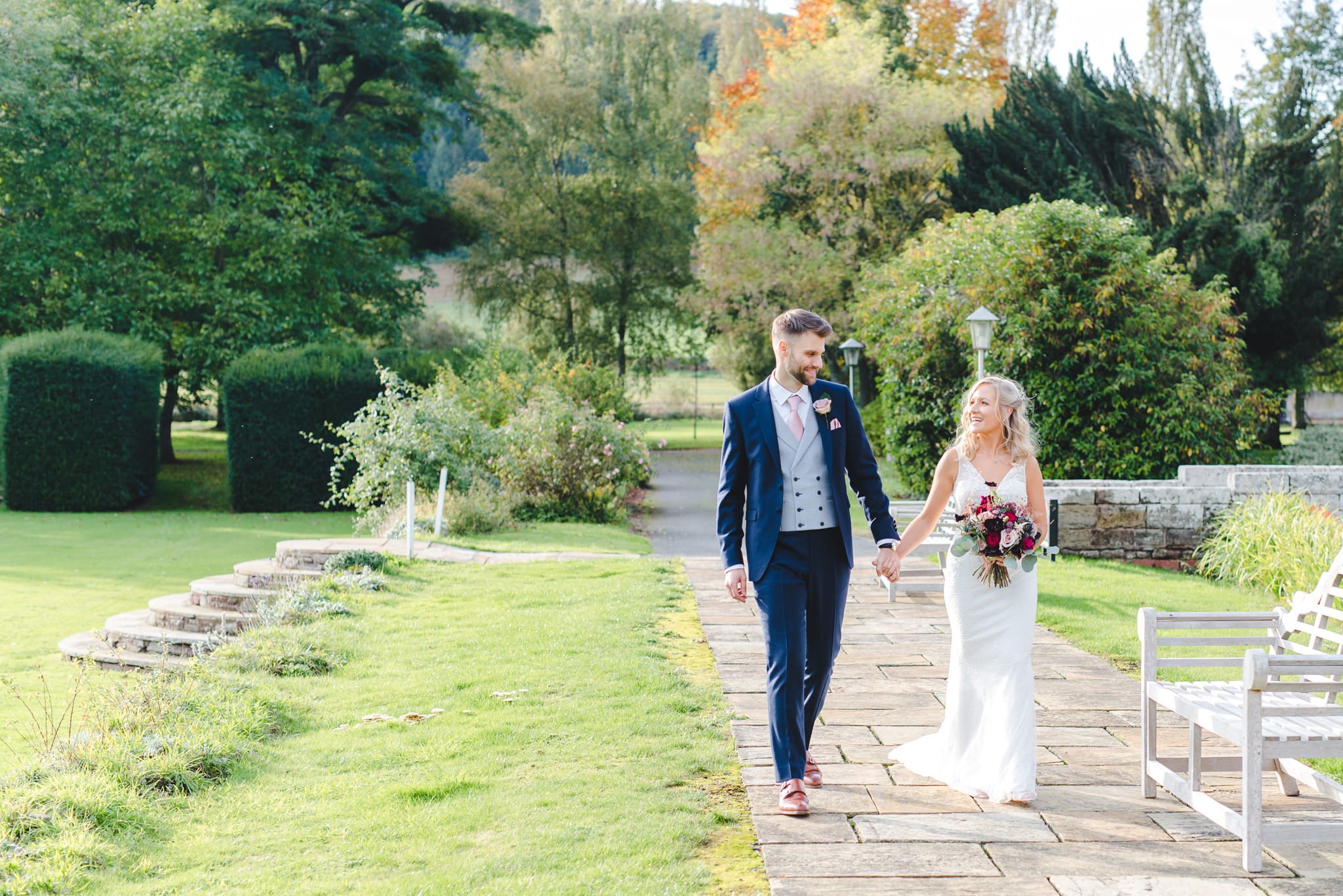 A bride and groom walking in the grounds at Brinsop Court