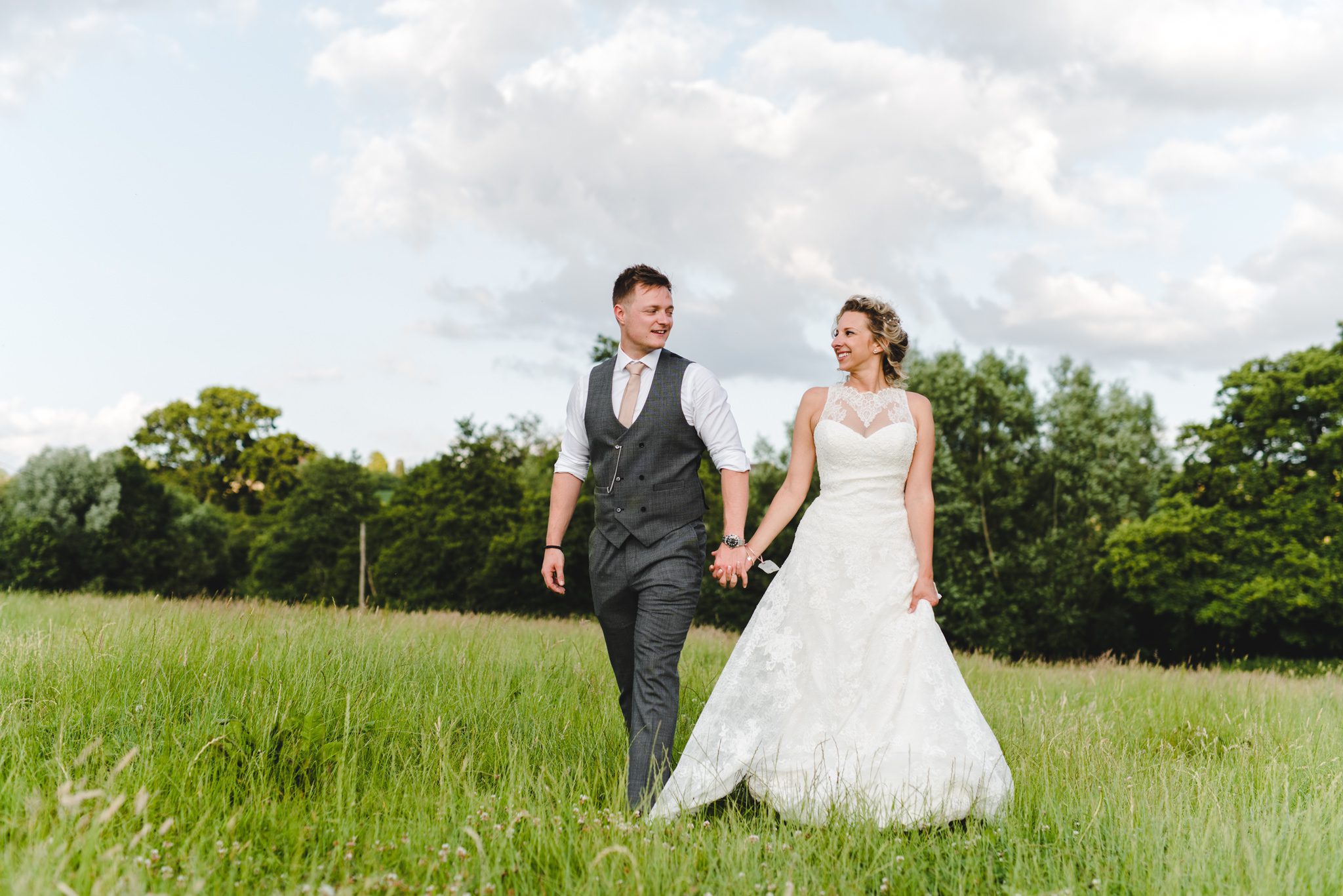 bride and groom walking in a field at Priston Mill