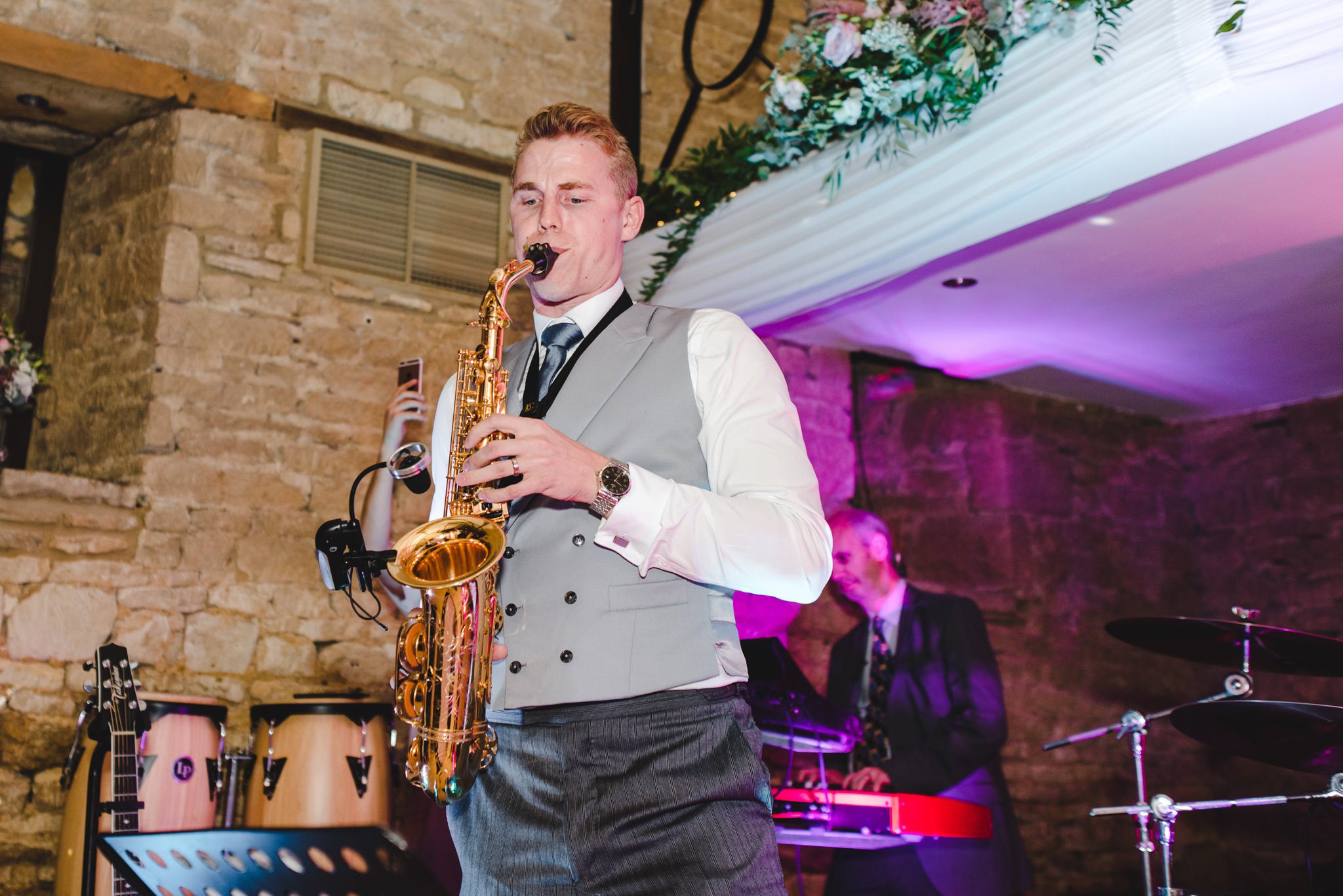 Groom playing the saxophone at his Great Tythe Barn wedding