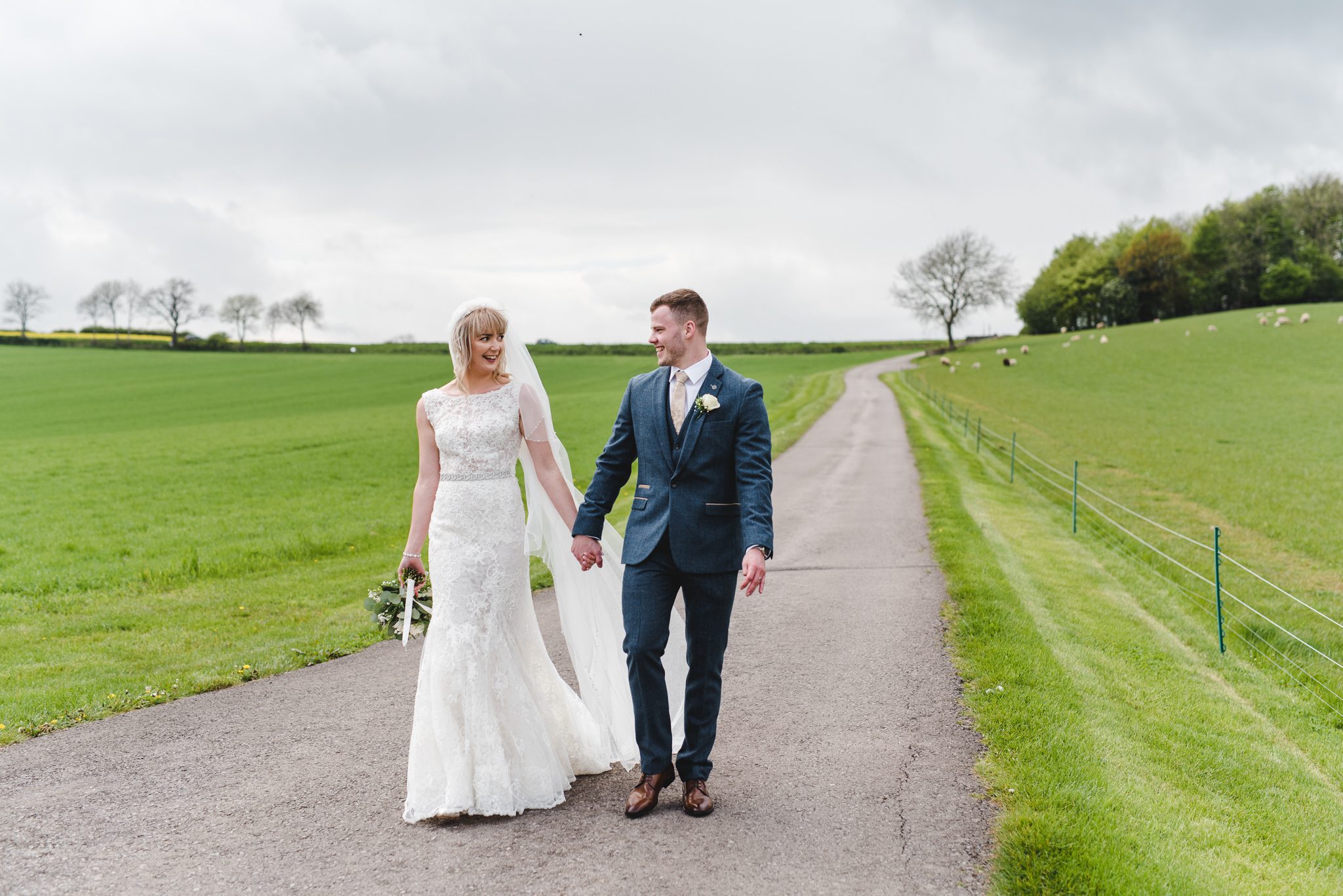 A bride and groom walking down the drive on their wedding day at Kingscote Barn