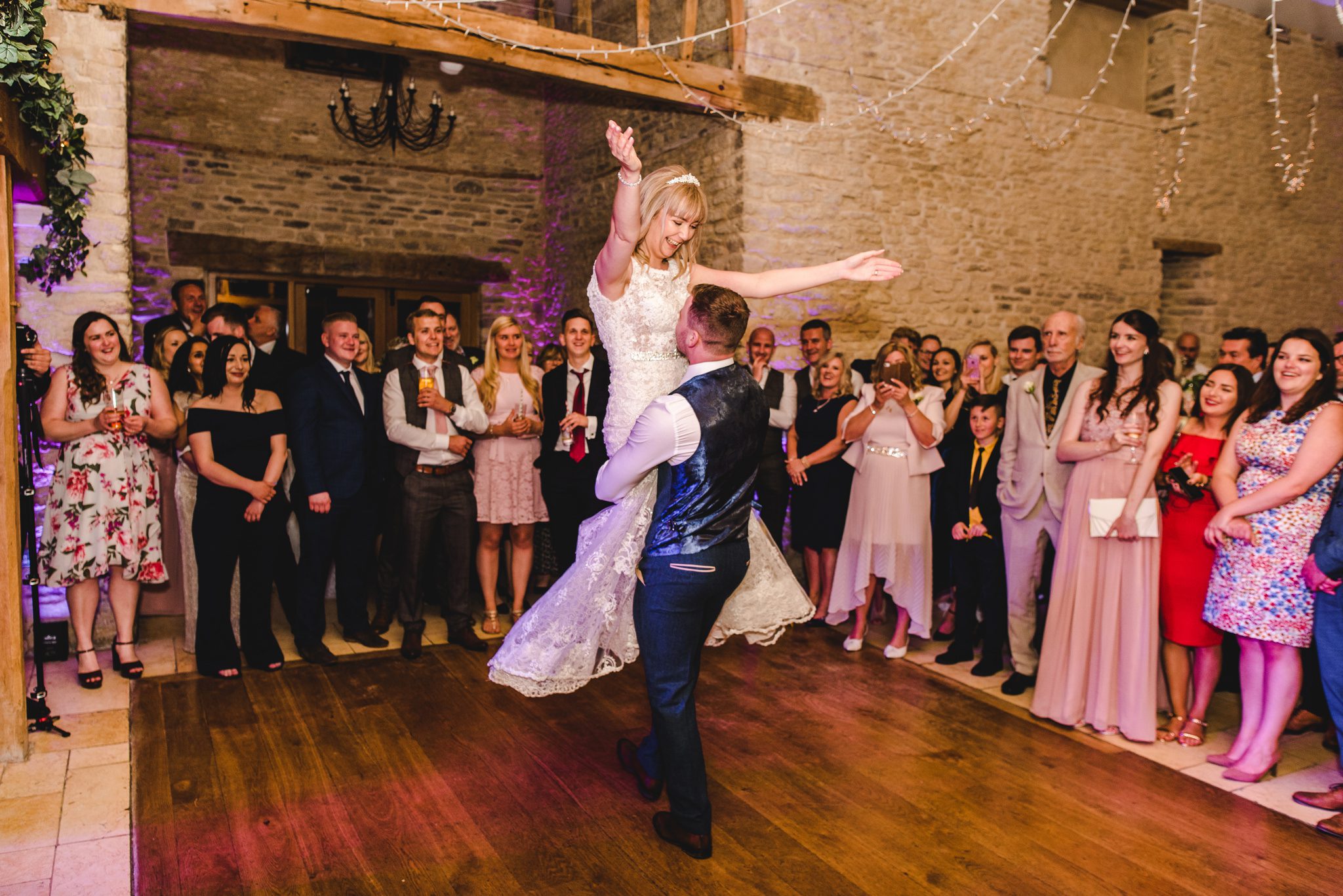 Groom lifting his bride up during their first dance at Kingscote Barn