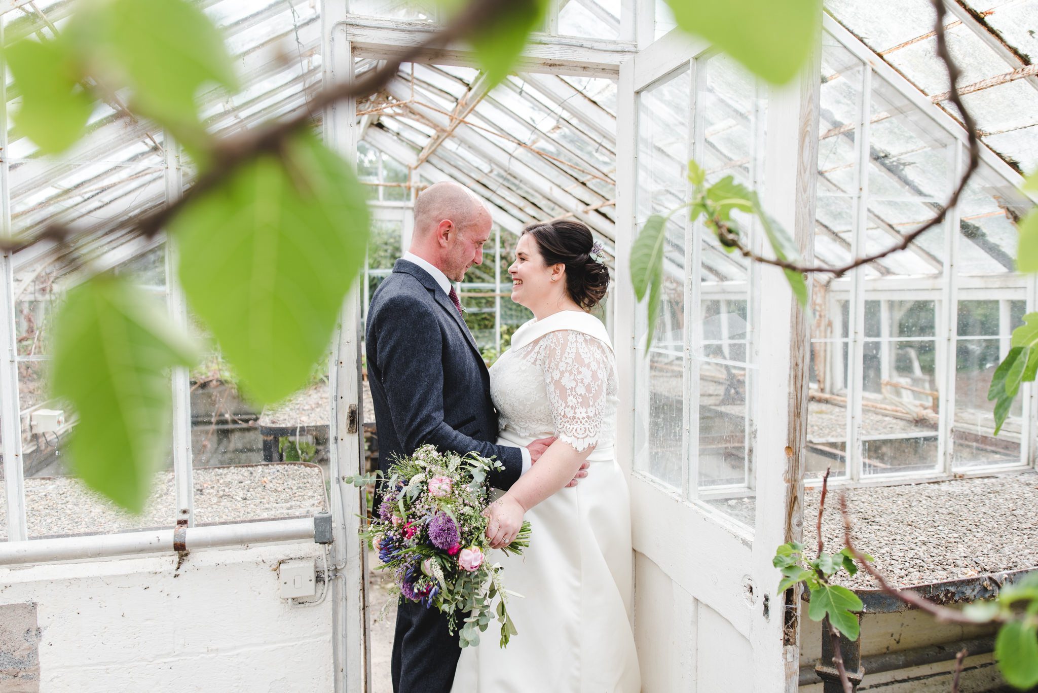 A couple in a greenhouse standing opposite each other