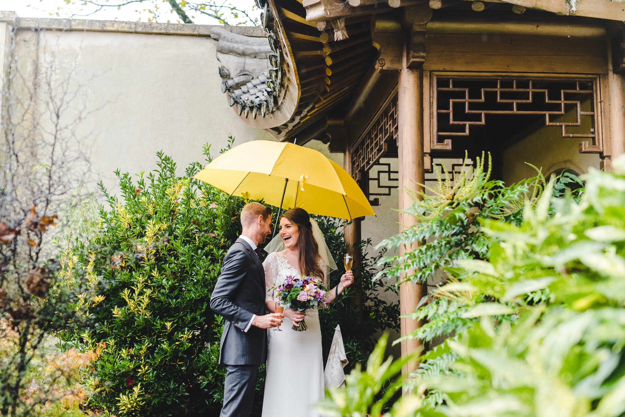 A bride and groom under a yellow umbrella