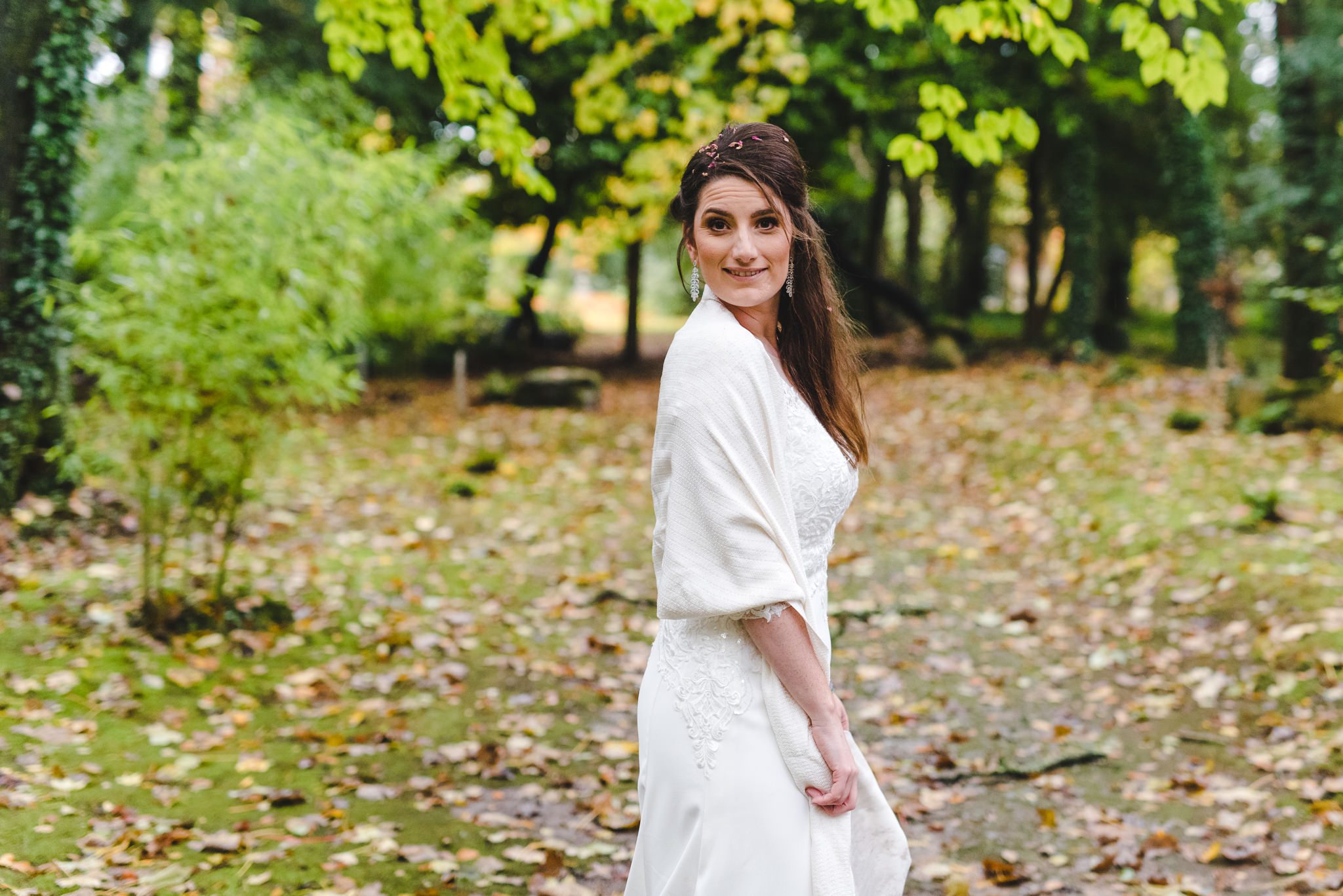 A bride stood in the woods in her wedding dress