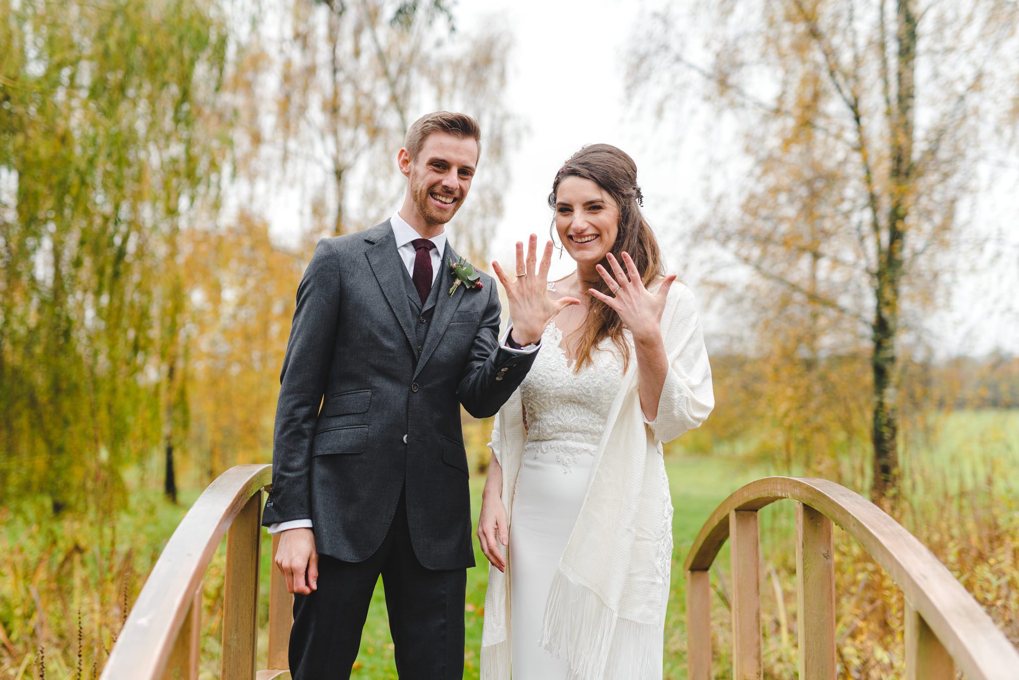 A bride and groom showing their wedding rings to the camera