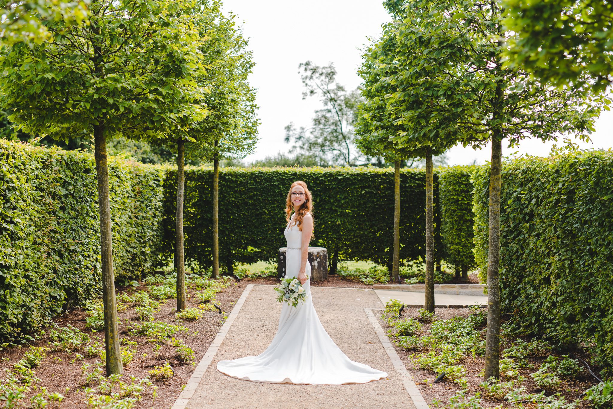 A bride standing on a path full length shot in her wedding dress