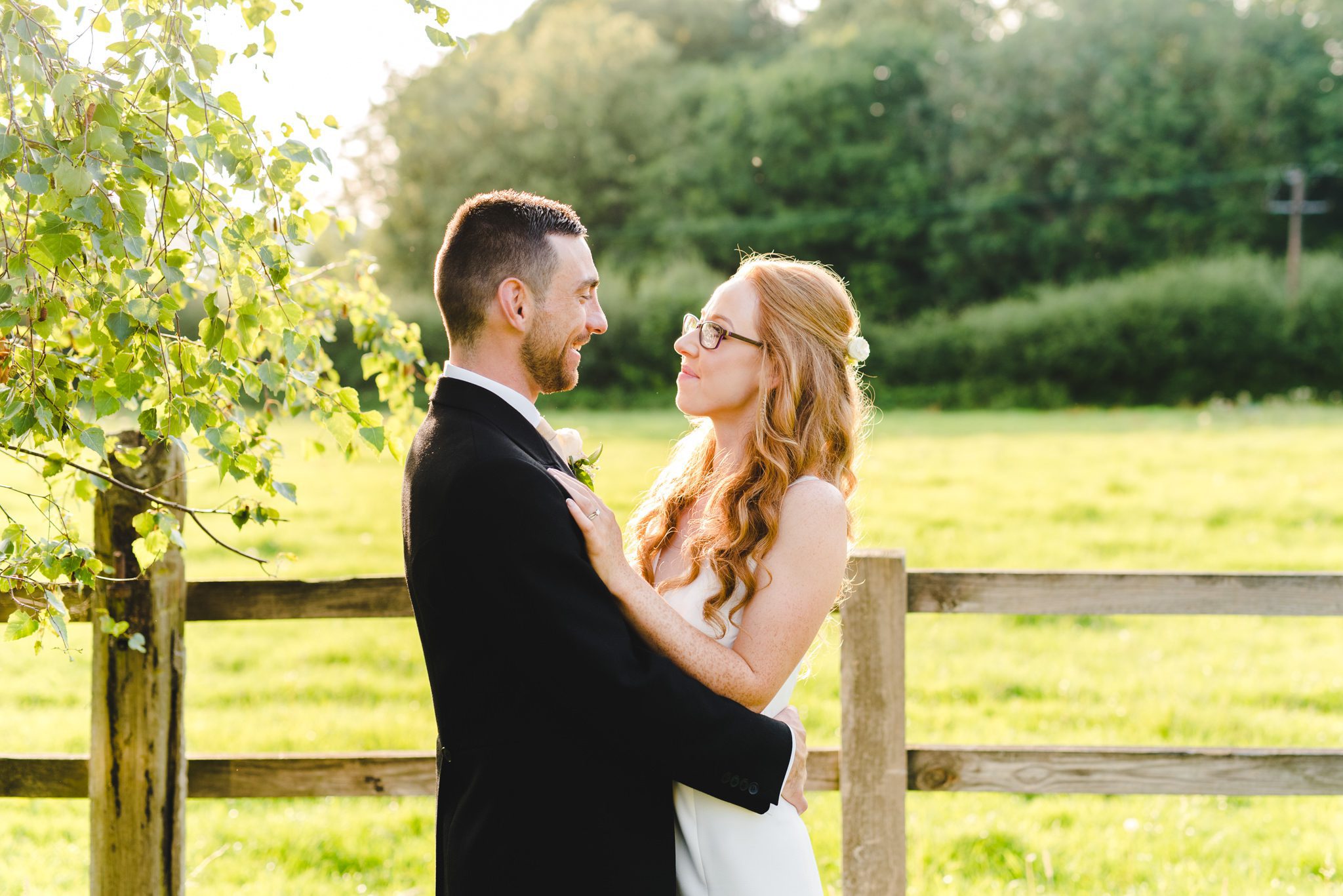 A bride and groom walking in the fields at sunset at Hyde House