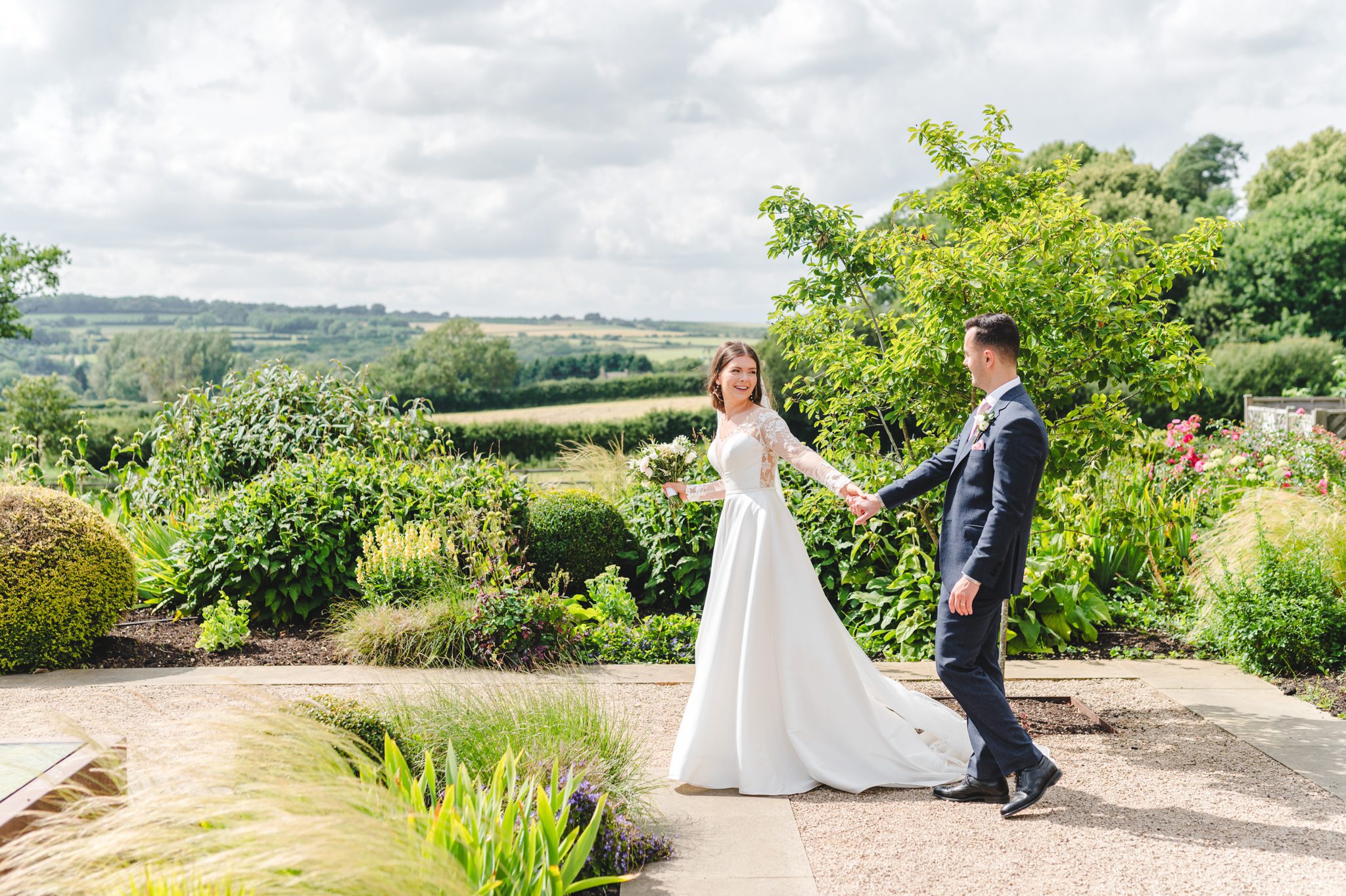 A bride and groom walking in The Cotswolds