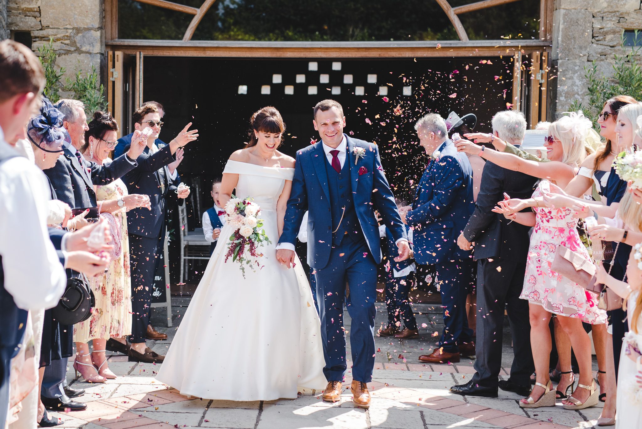 Bride and groom walking through confetti at Oxleaze