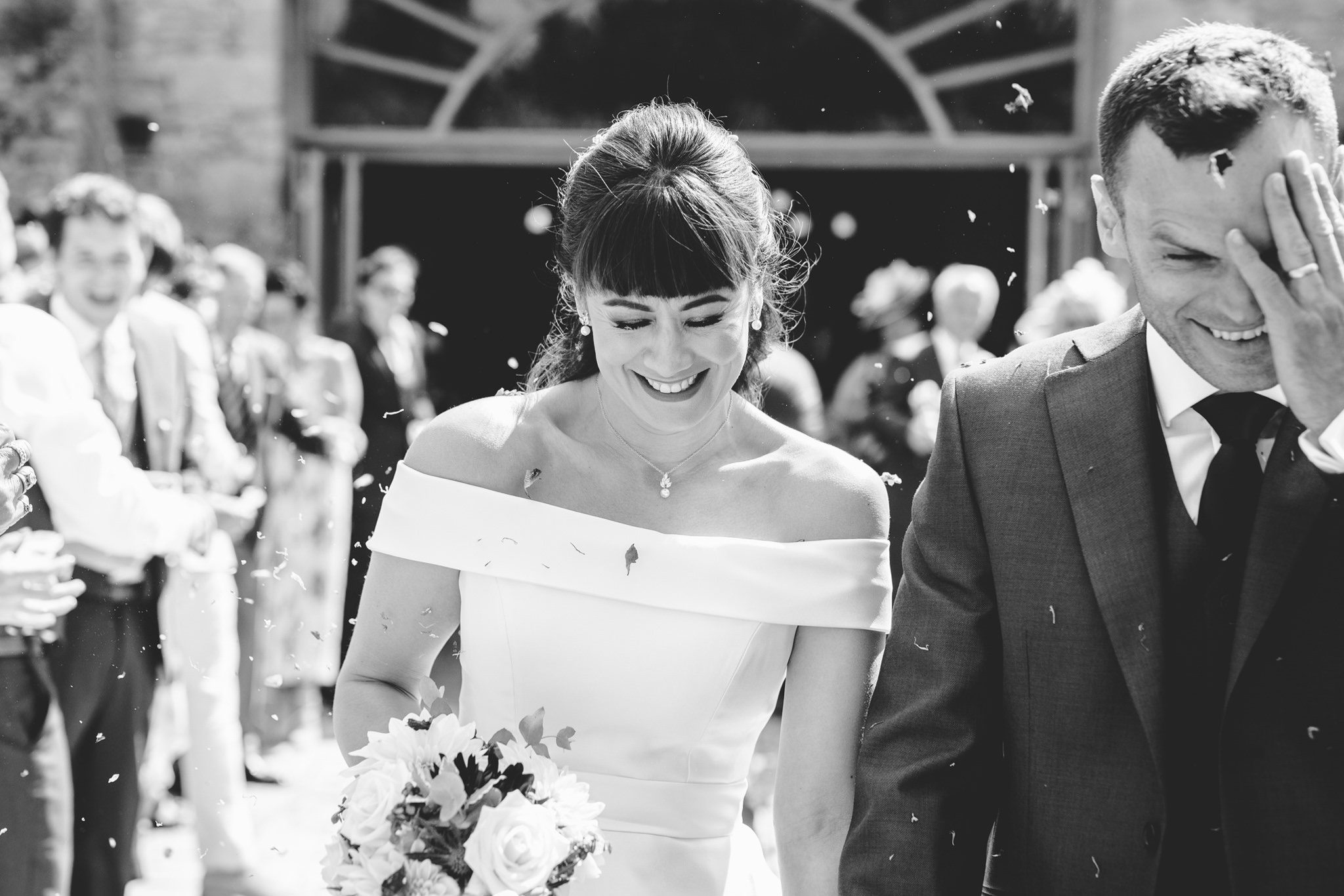 Bride and groom walking through confetti at Oxleaze