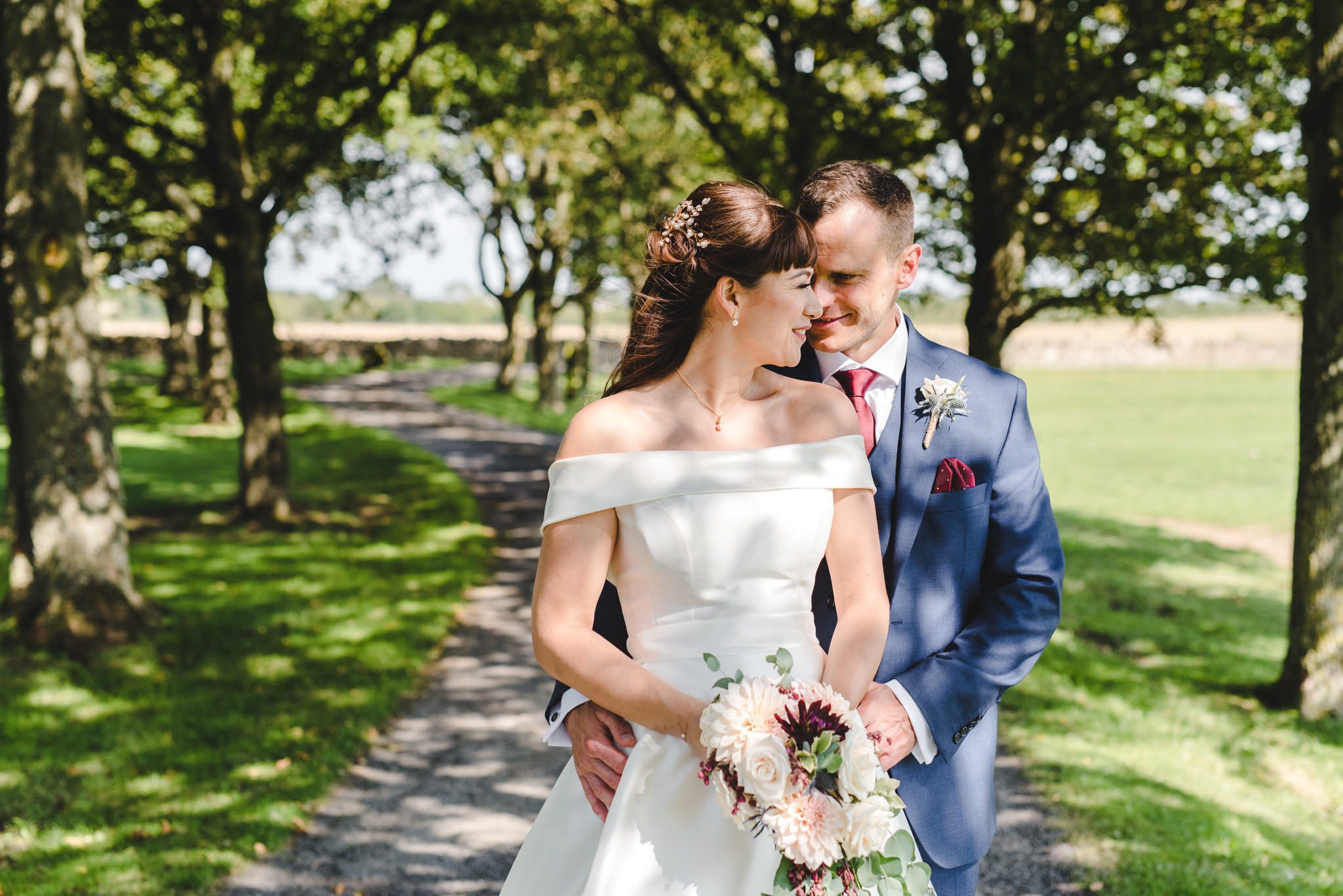 A couple stood in dappled light at their wedding